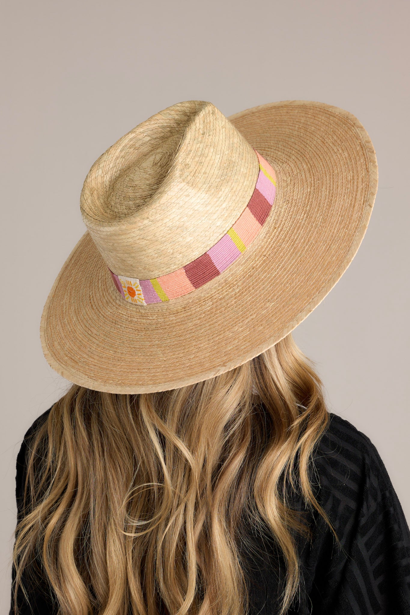 Back view of this hat that features a woven striped band, and is handmade with palm fronds.