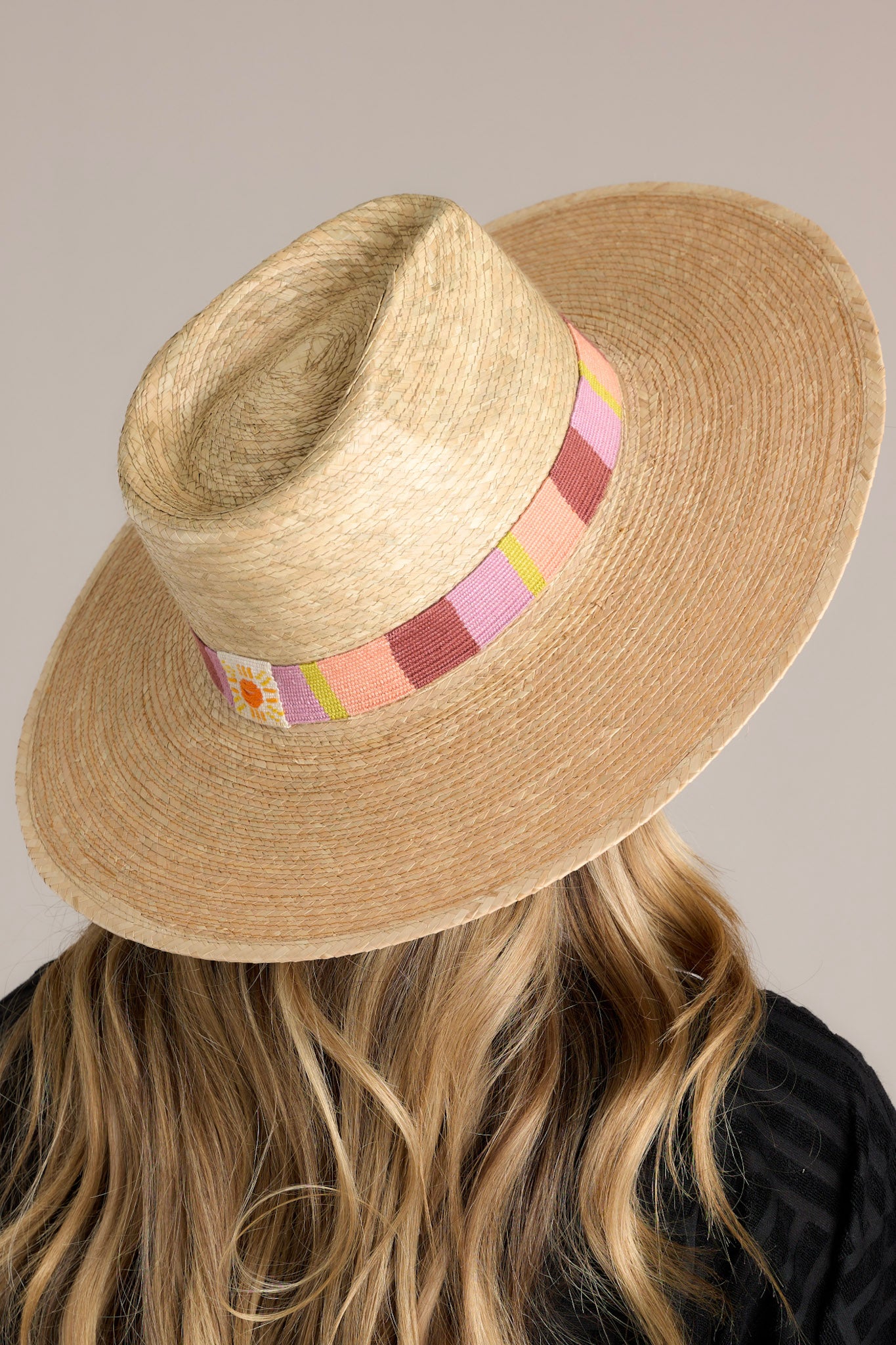 Close-up view of this hat that features a woven striped band, and is handmade with palm fronds.