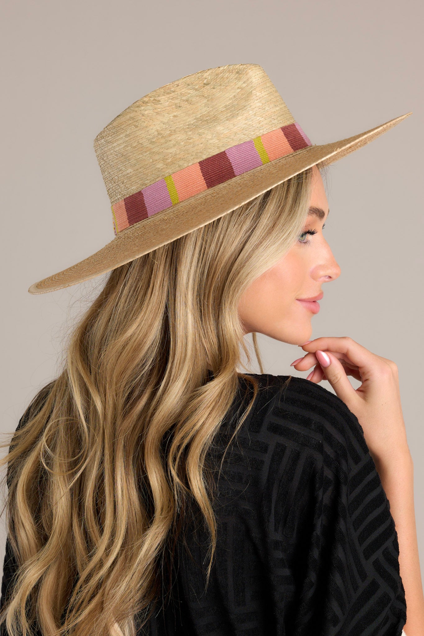 This hat features a woven striped band, and is handmade with palm fronds.