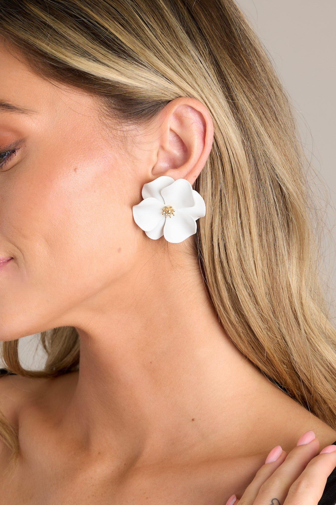 These white earrings feature gold hardware, white flowers with defined petals, and secure post backings.