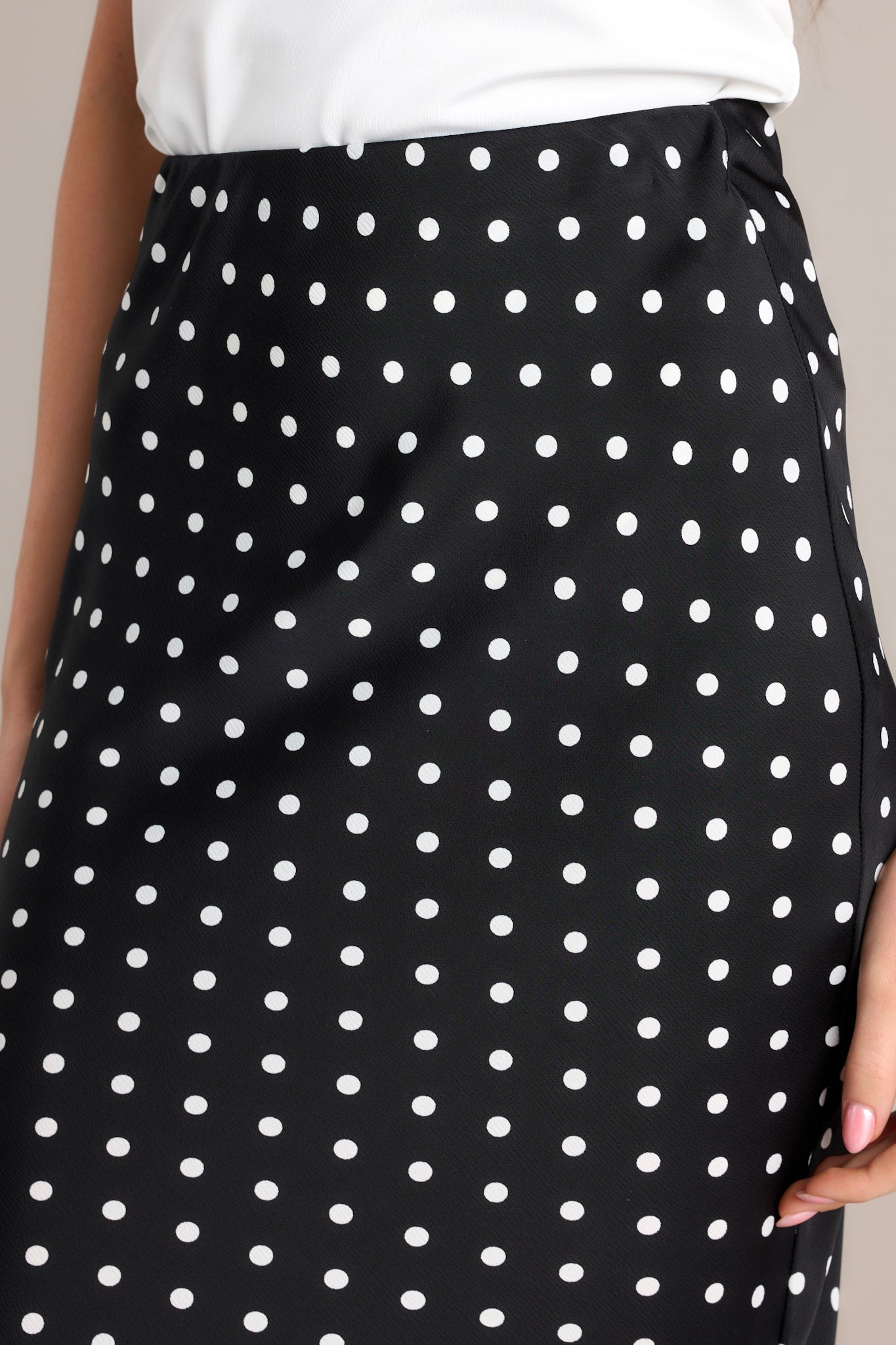 Detail shot of the black midi skirt's fabric, highlighting the intricate timeless pattern and quality material.