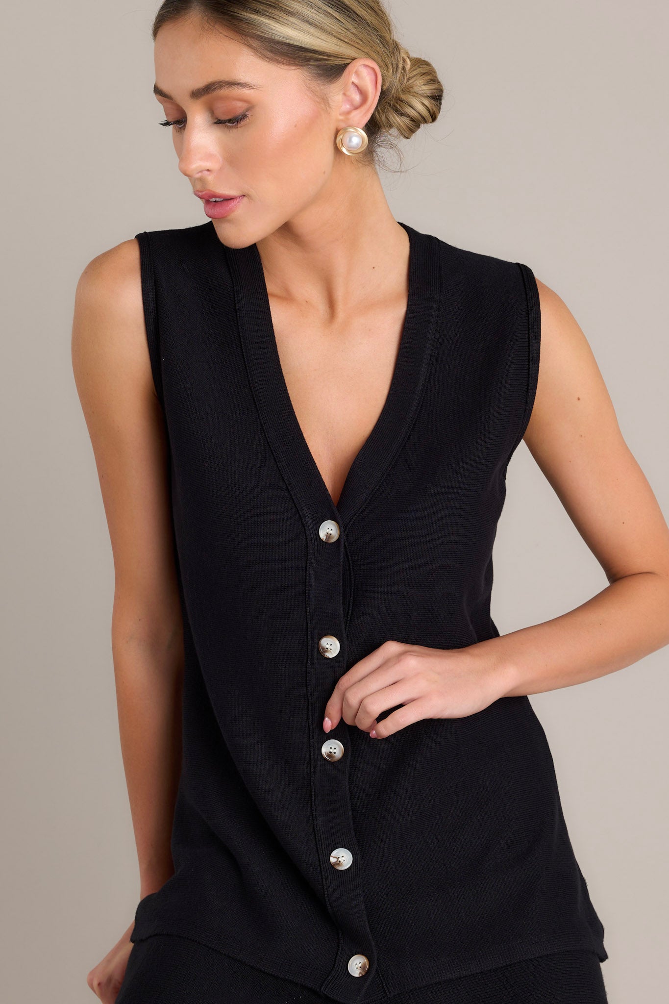 This black button front top features a sleeveless style, and functional tortoise shell buttons.