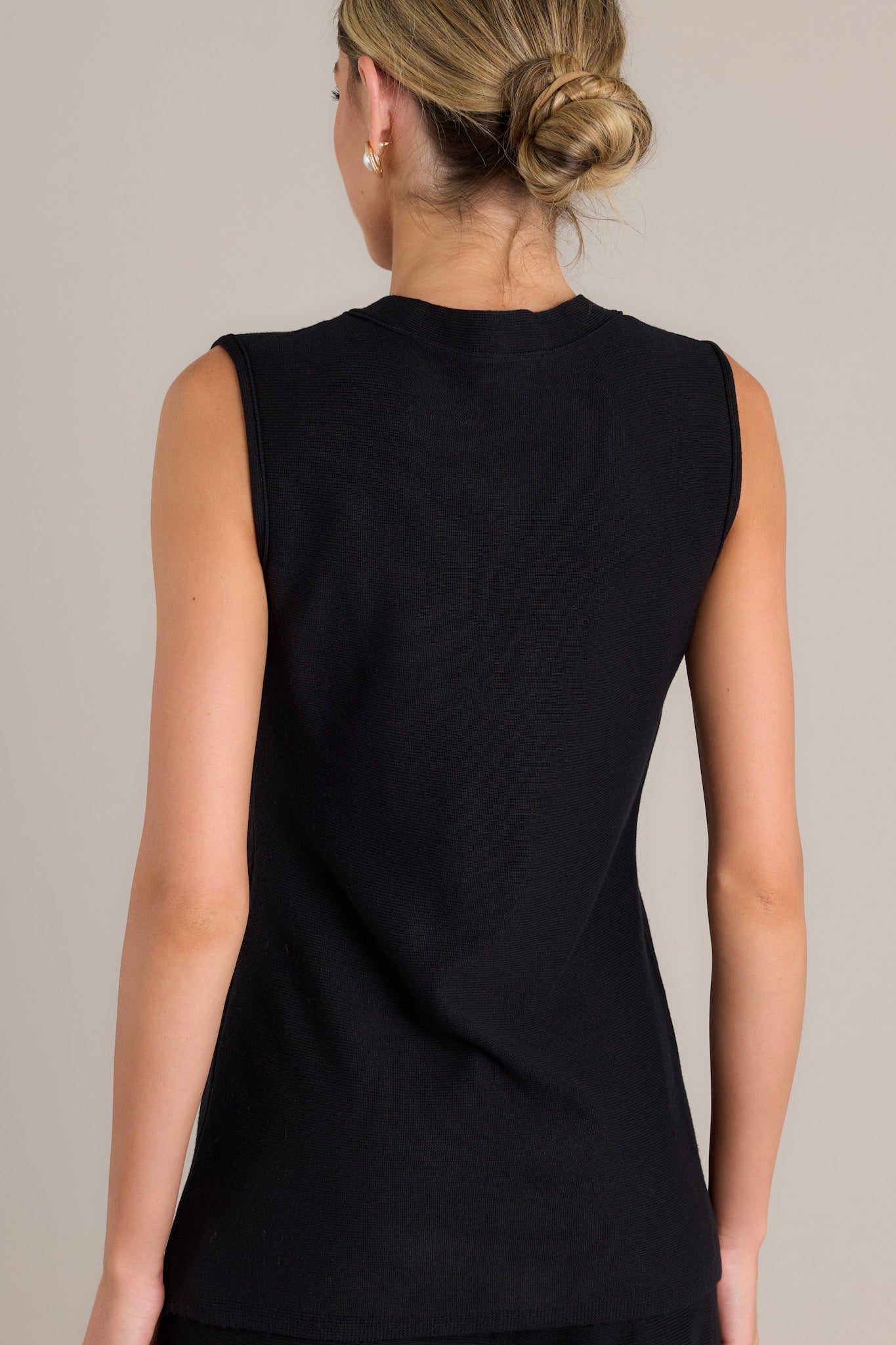 Back view of this black sleeveless top features functional buttons down the front, and a lightweight knit fabric. 