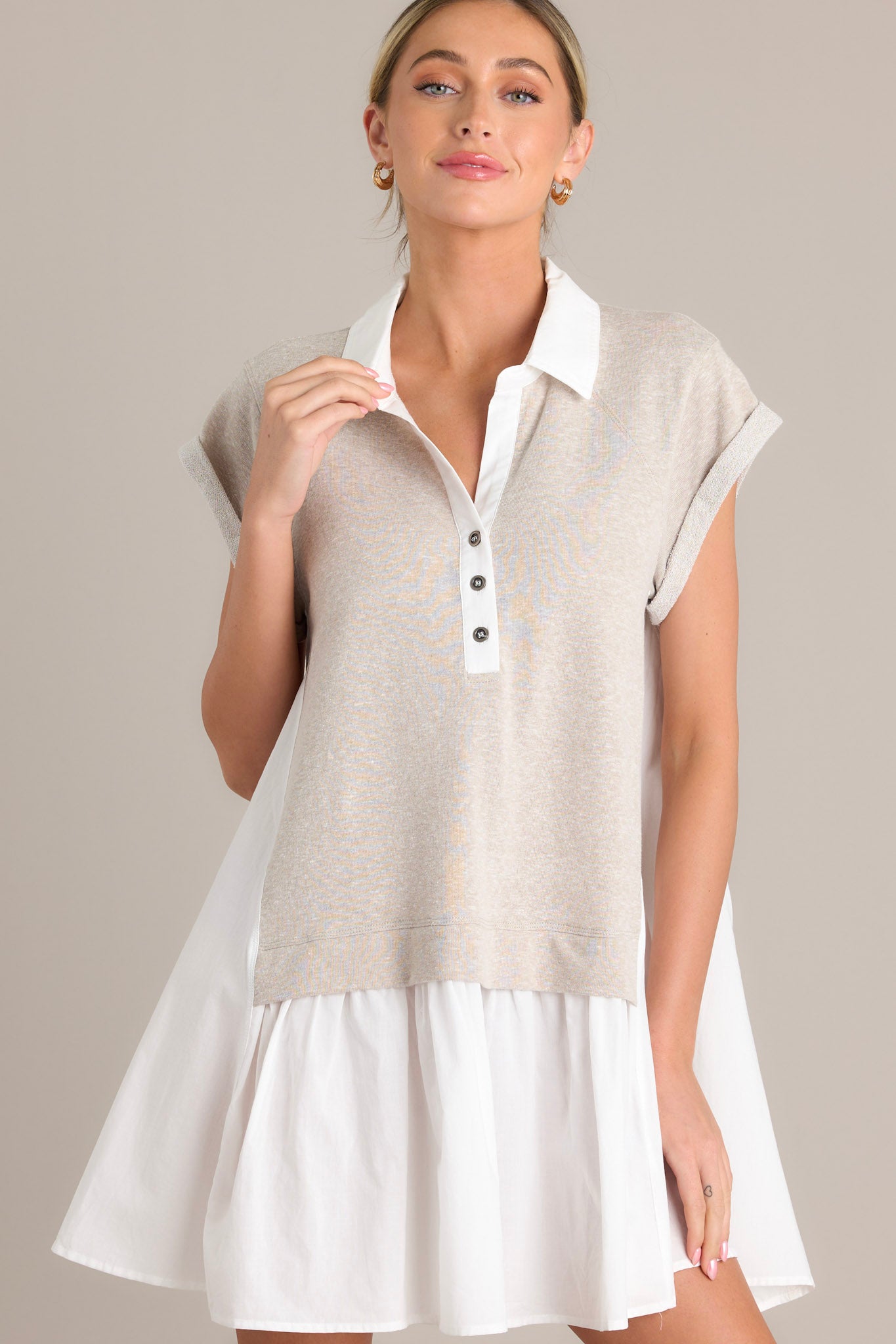 Front view of a taupe mini dress featuring a collared v-neckline, functional chest buttons, an attached sweater overlay, and cuffed short sleeves.