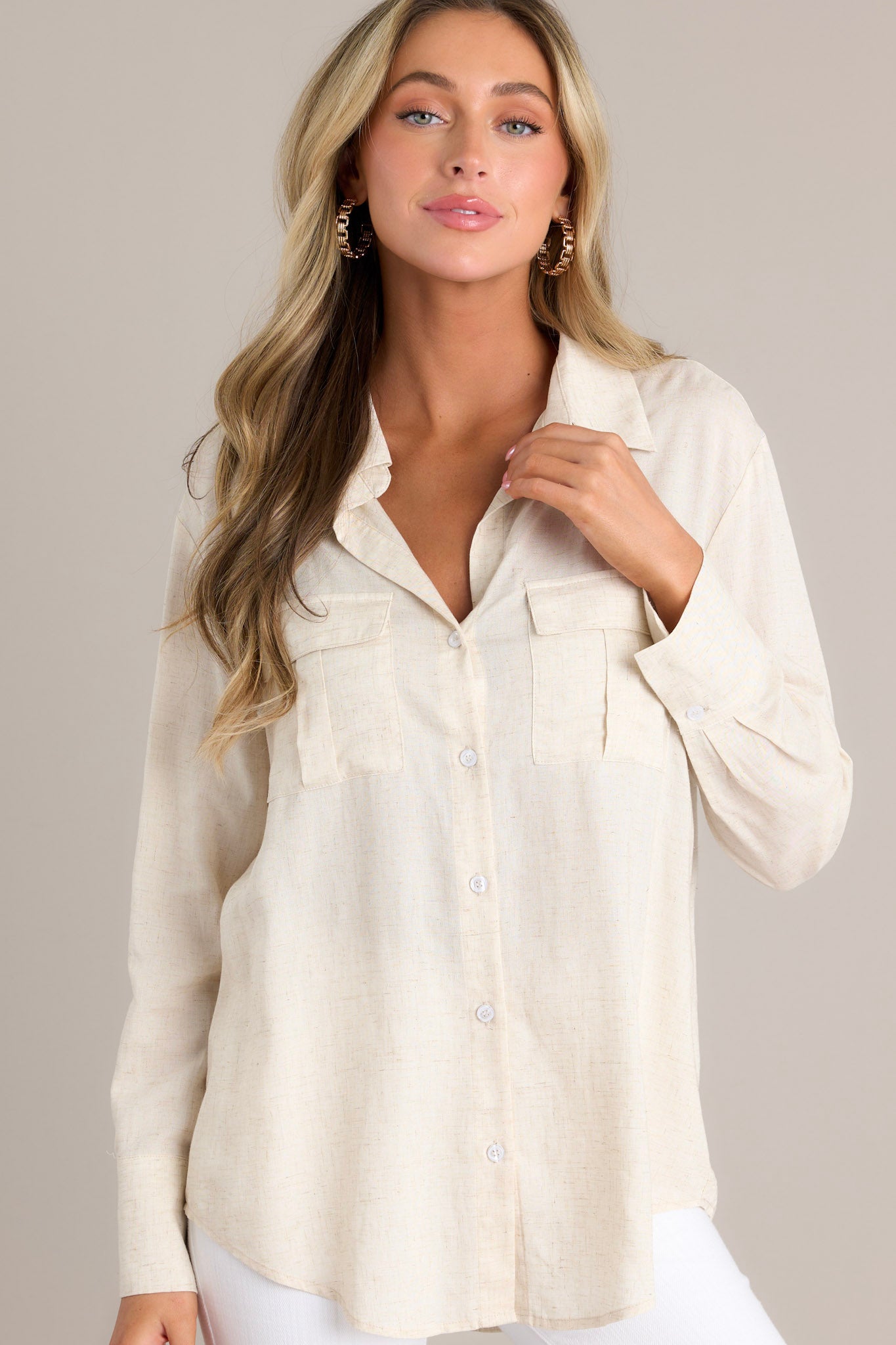 This natural colored top features a collared v-neckline, a full button front, functional chest pockets, and buttoned cuffed long sleeves. 