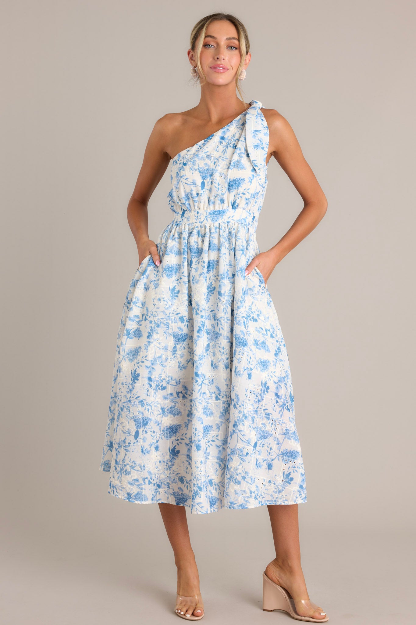 This blue floral dress features functional hip pockets, and embroidered detailing throughout. 