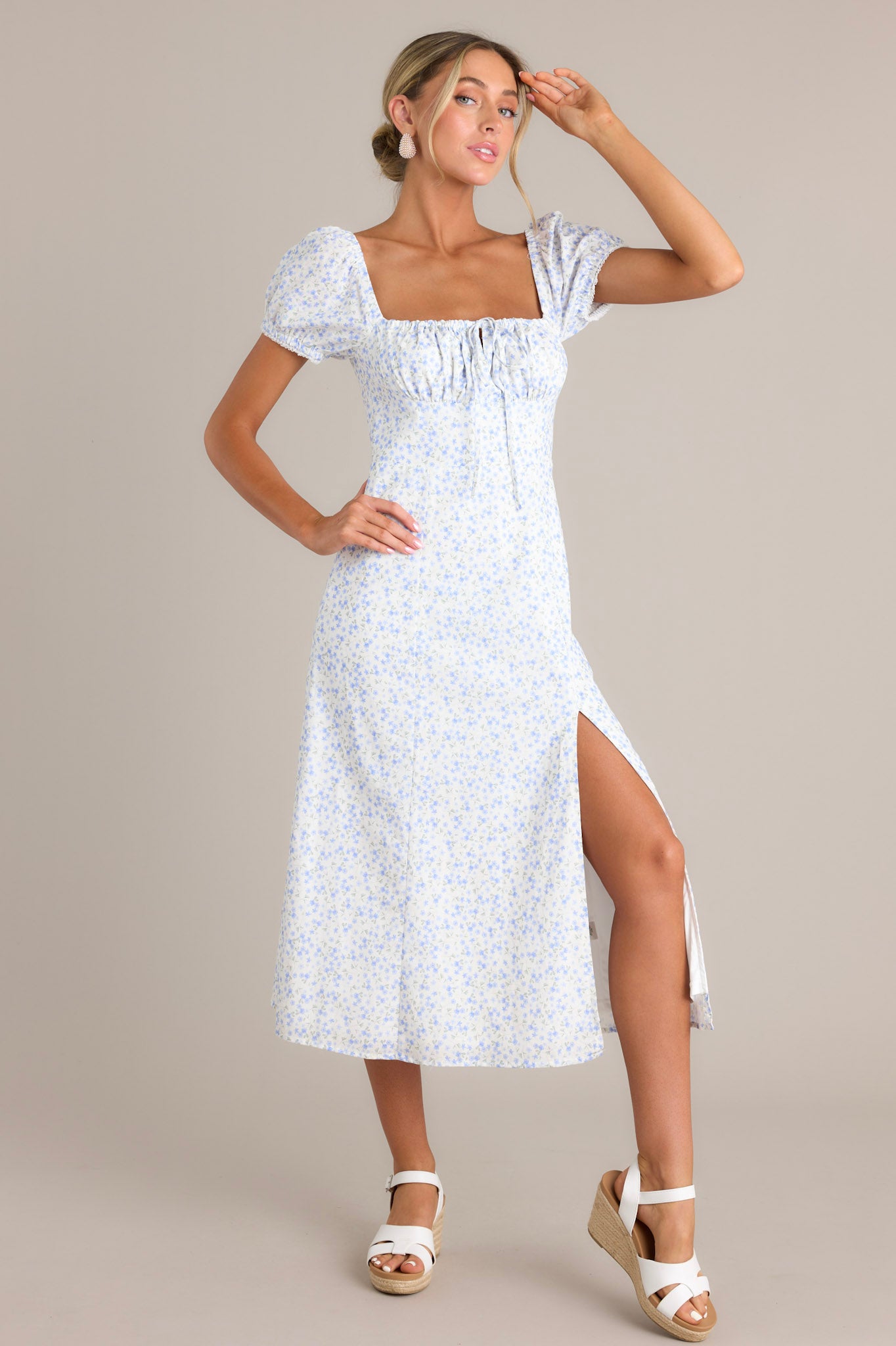 This light blue and white floral print dress features a ruched bust, puff sleeves, square neckline, and a front slit.