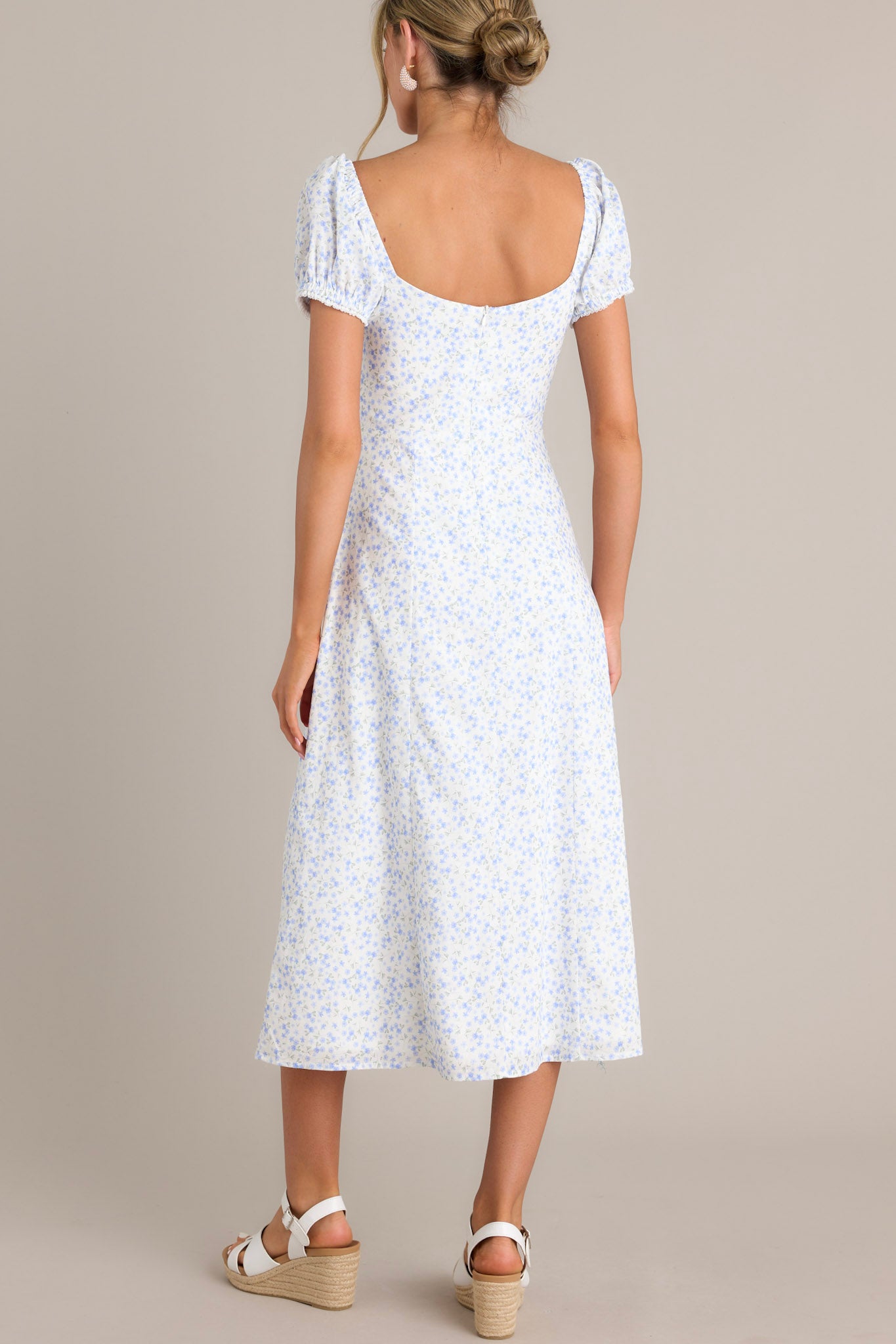 Back view of this light blue floral print dress, showcasing the square neckline and fitted silhouette, with puff sleeves and a flowing skirt.