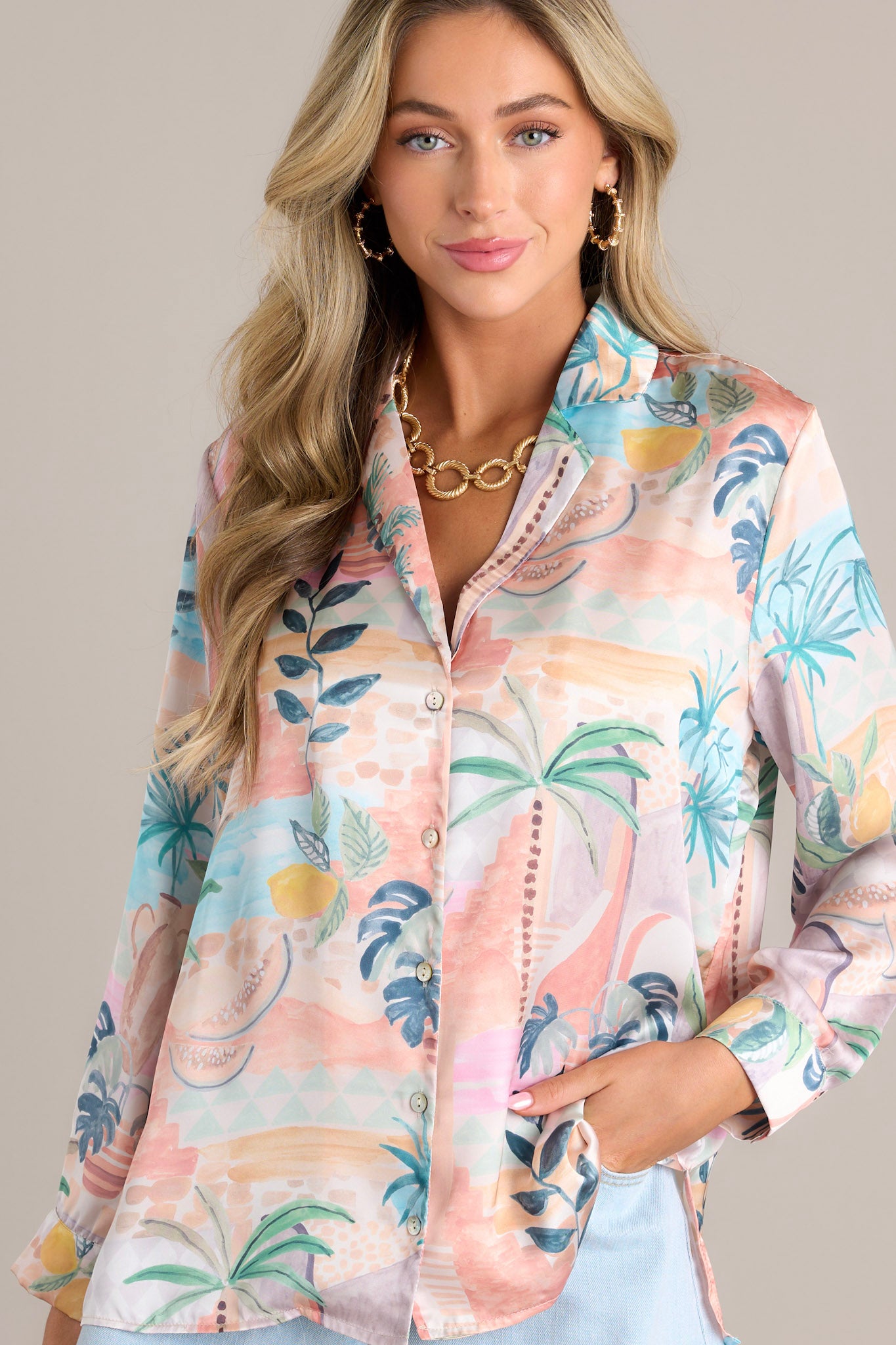 Front view of a peach top featuring a notched lapel collared neckline, functional button front, button cuffed long sleeves, and a split hemline.