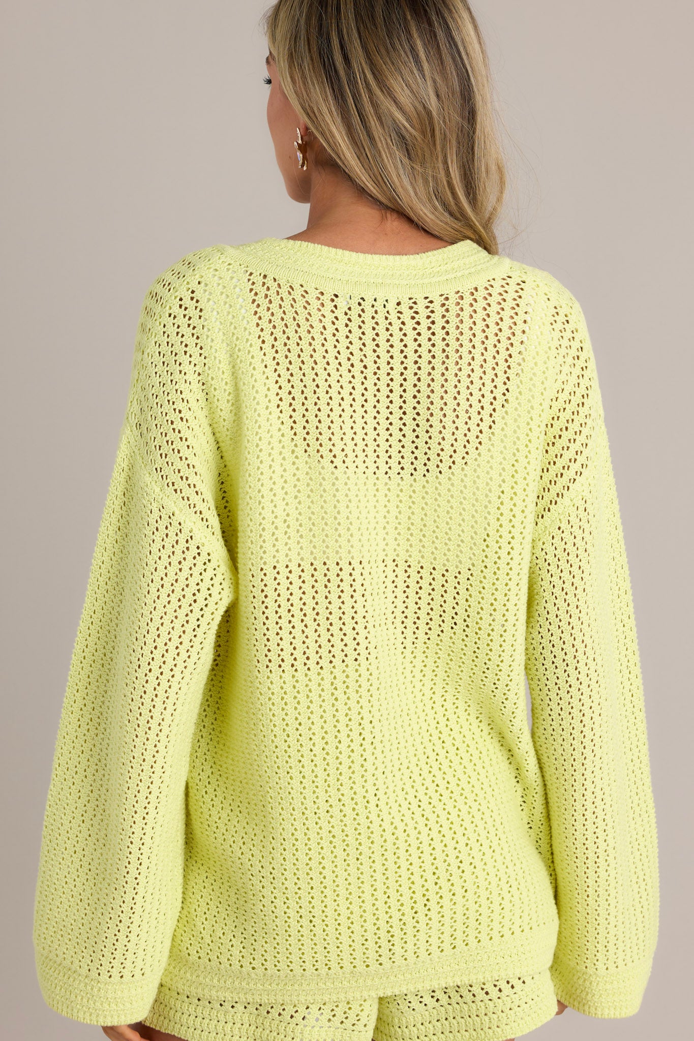 Back view of a lime sweater featuring a relaxed fit and an open knit design.