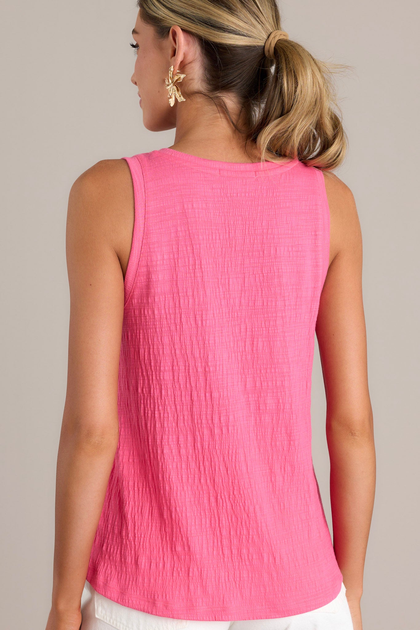 A back view of the pink tank top, displaying the sleeveless design and textured material.