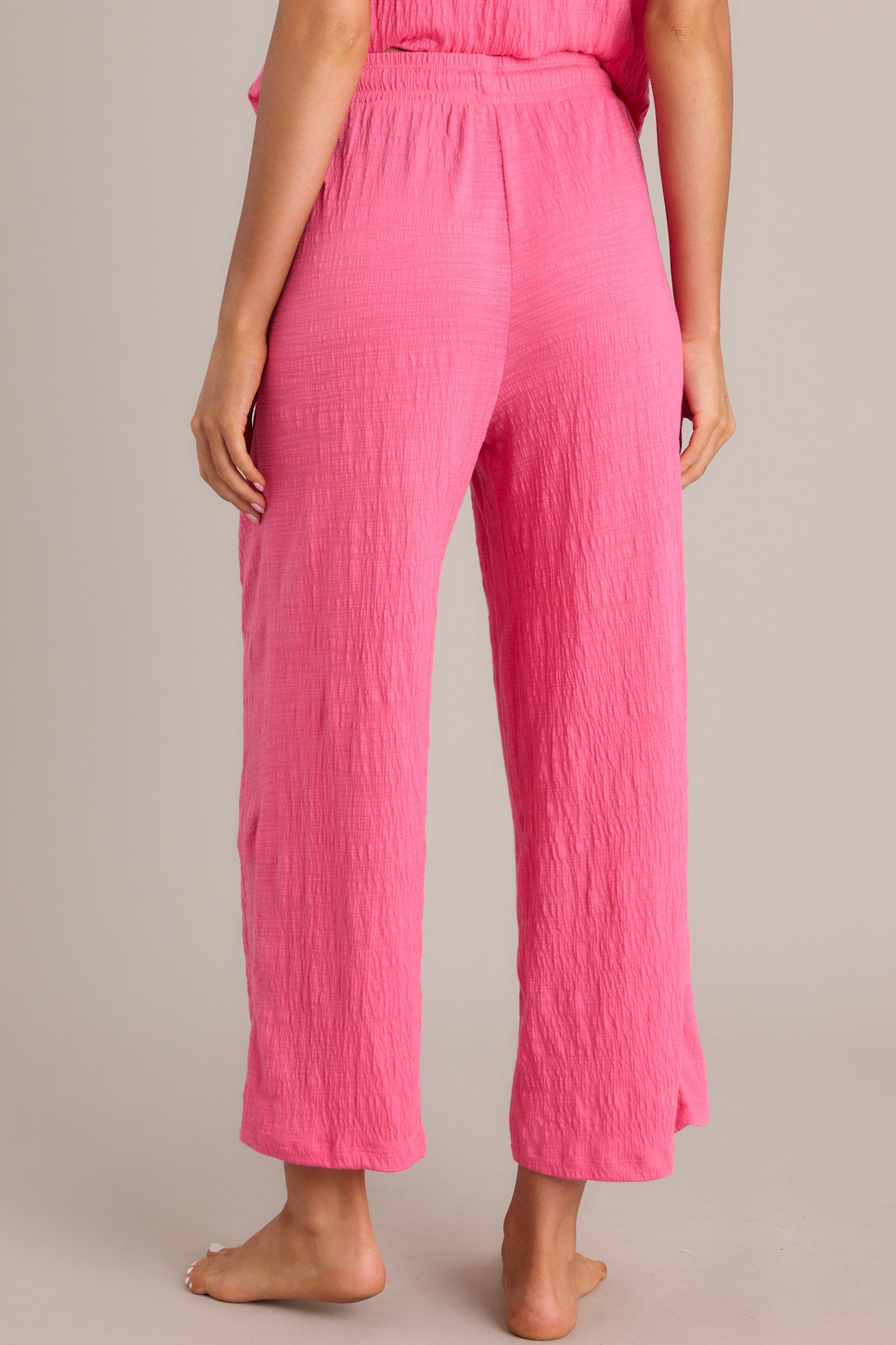 Back view of pink pants displaying the high-waisted design, elastic waistband, and wide leg.