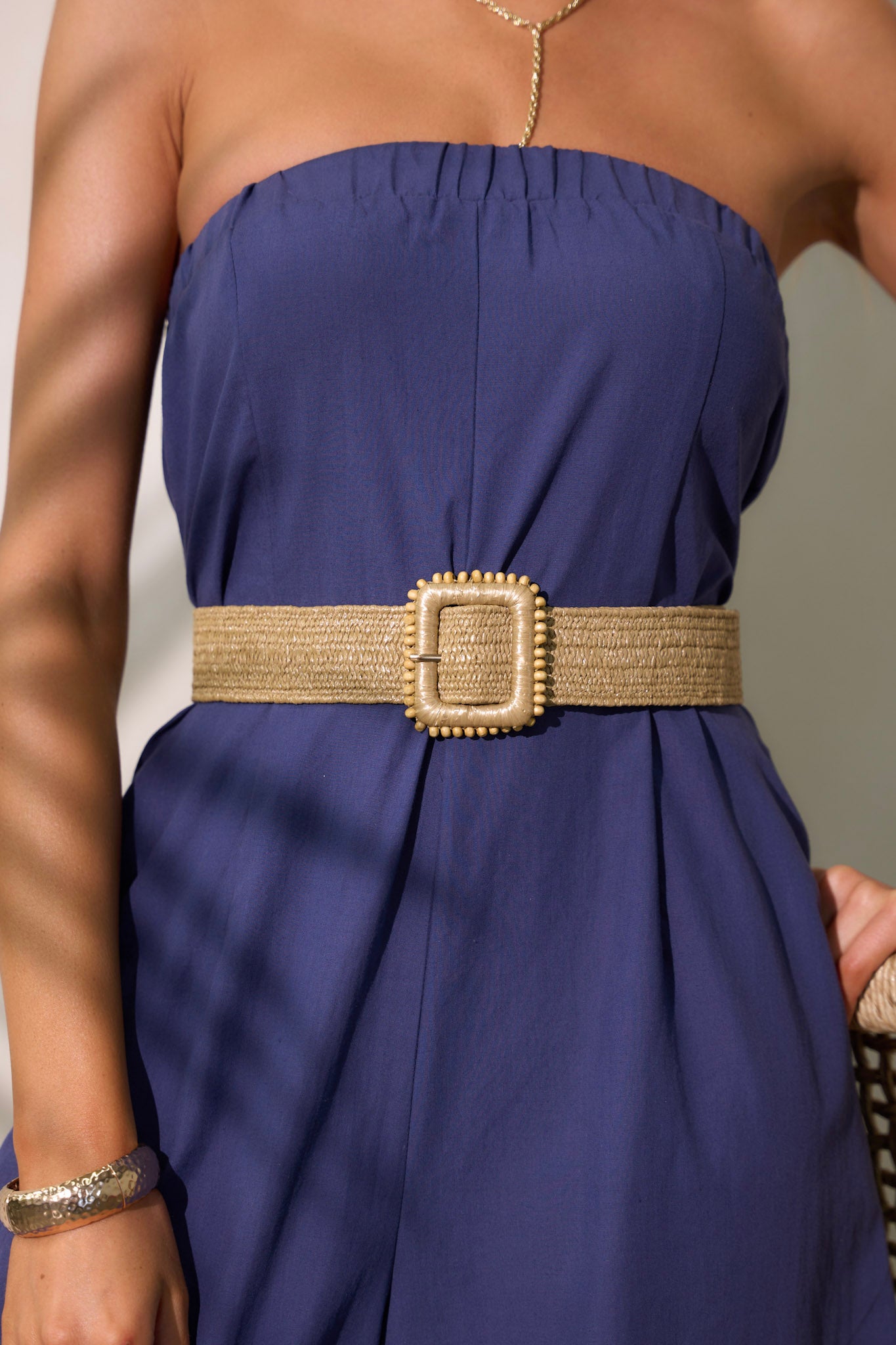 This straw belt features a square buckle, beaded detailing and a faux straw material.