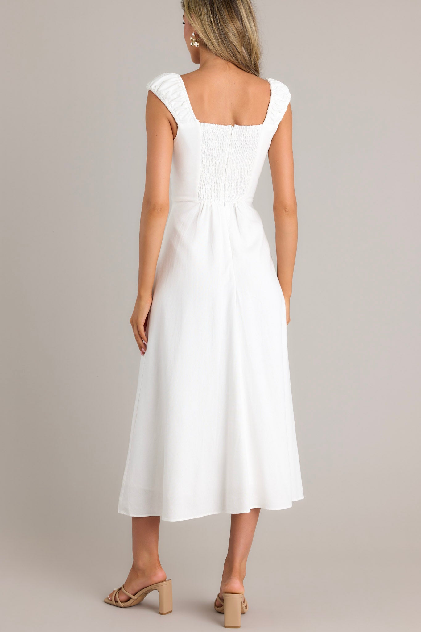 Back view of a white midi dress showcasing the smocked back section, hidden zipper, smocked sleeves, and flowy skirt.