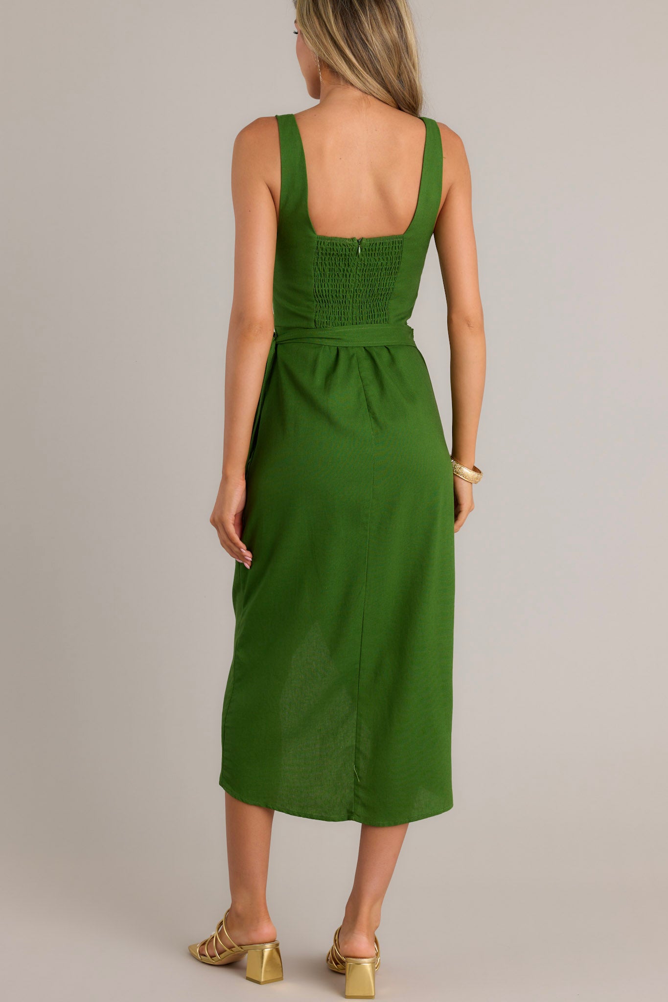 Back view of a green midi dress highlighting the smocked back insert and discrete zipper.