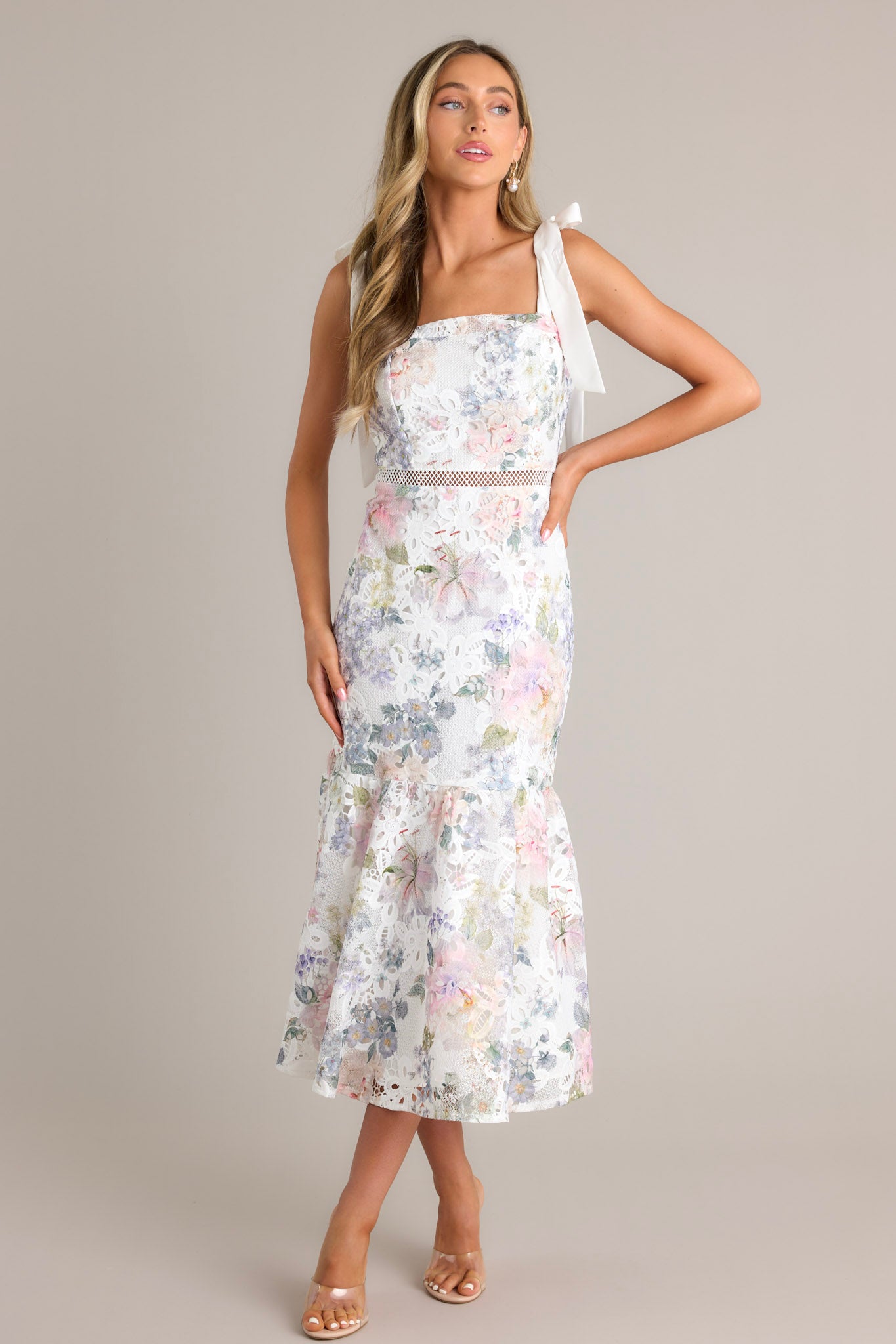 Front view of this ivory floral midi dress that features a square neckline, self-tie straps, a hidden zipper down the back, a single-tier design, and a lace knitted overlay.