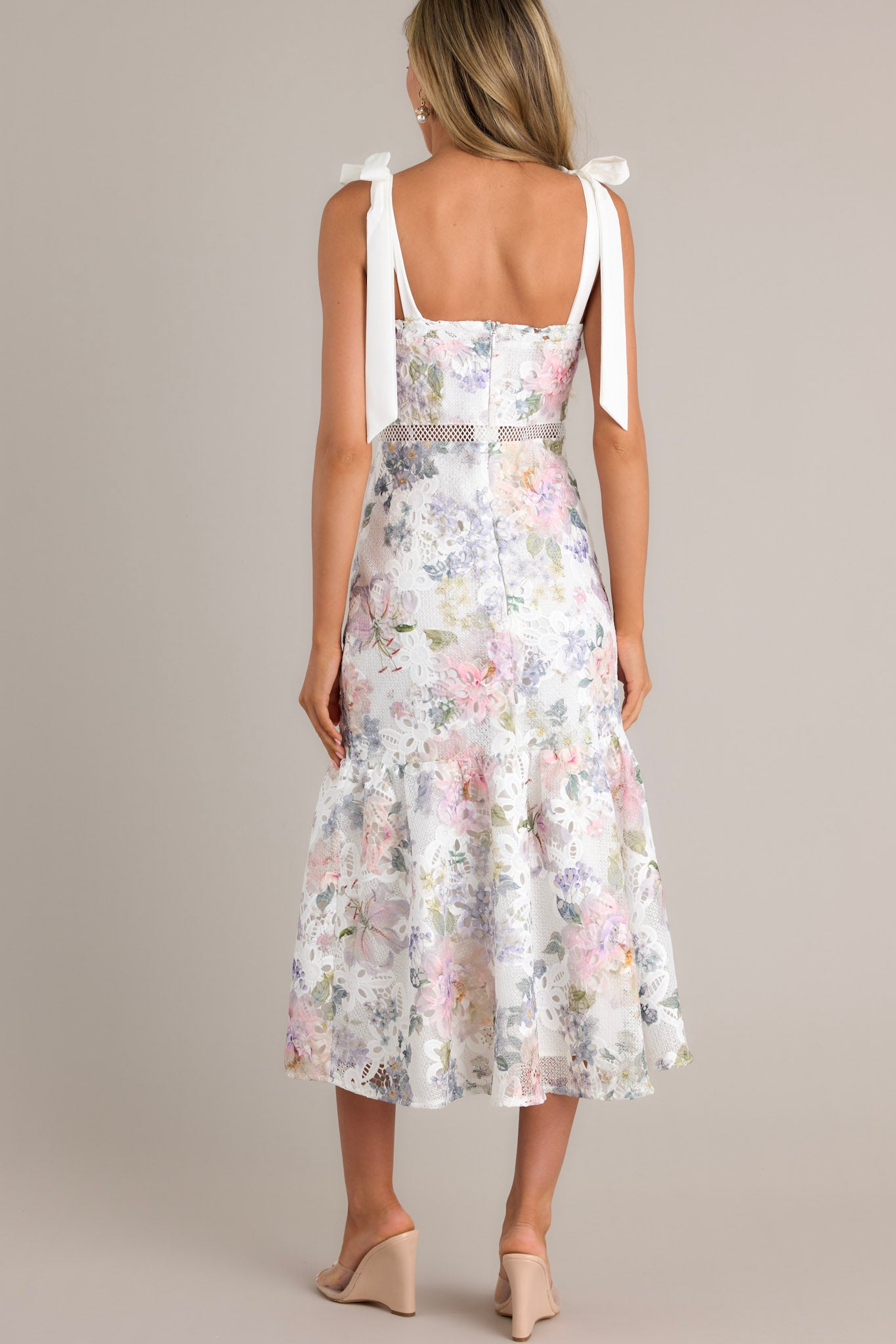 Back view of this ivory floral midi dress that features a square neckline, self-tie straps, a hidden zipper down the back, a single-tier design, and a lace knitted overlay.