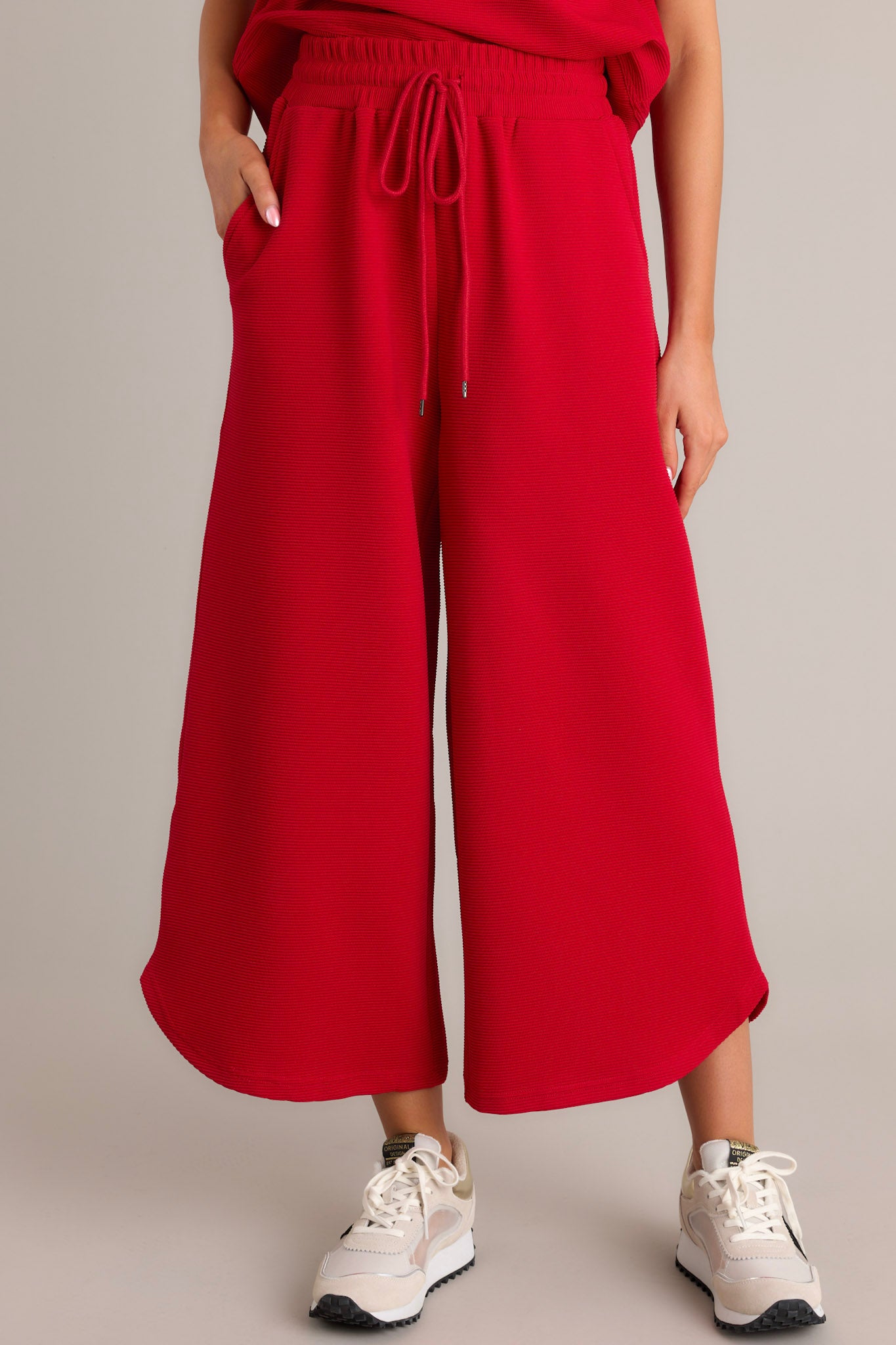 Close-up of the red pants focusing on the ribbed texture, elastic waistband, and self-tie drawstring.