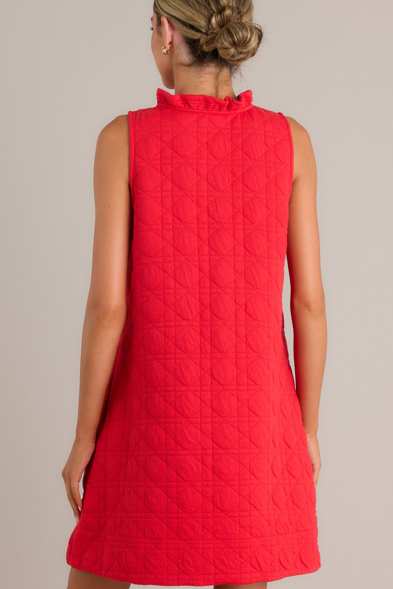 Back view of a red mini dress highlighting the unique quilted material and sleeveless design.