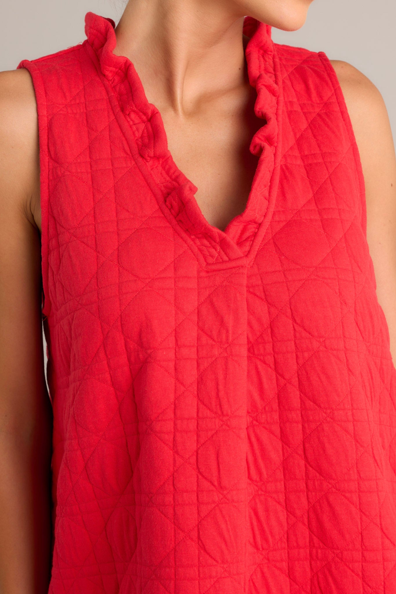 Close-up of the red mini dress showing the ruffled v-neckline, unique quilted material, and functional hip pockets.