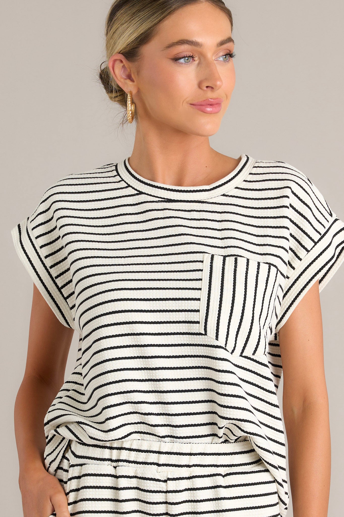 Close-up of a striped top showing the crew neckline, horizontal stripes, and the breast pocket with vertical stripes.