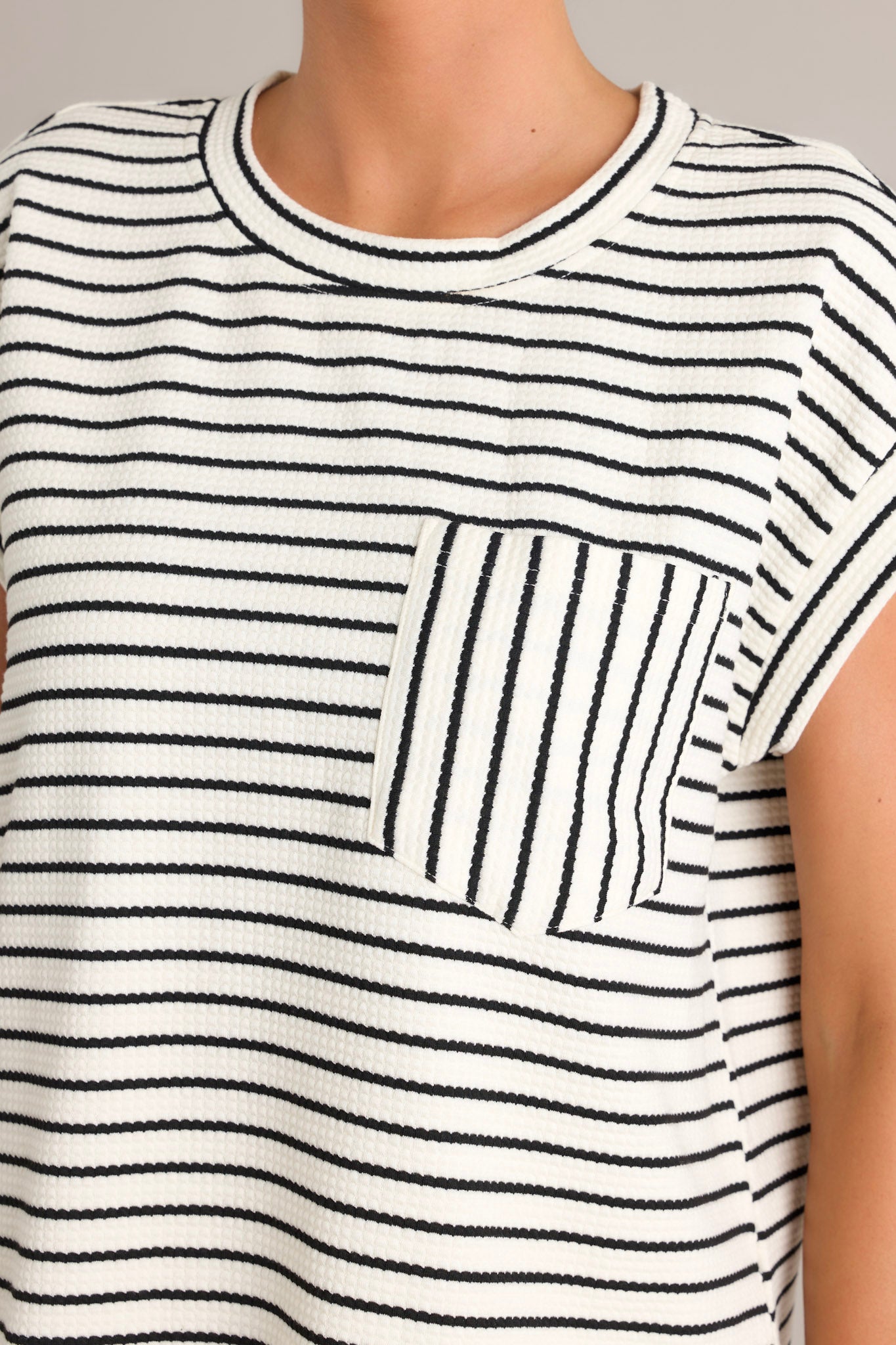 Close-up of the striped top emphasizing the wide cuffed sleeves and the breast pocket with vertical stripes.