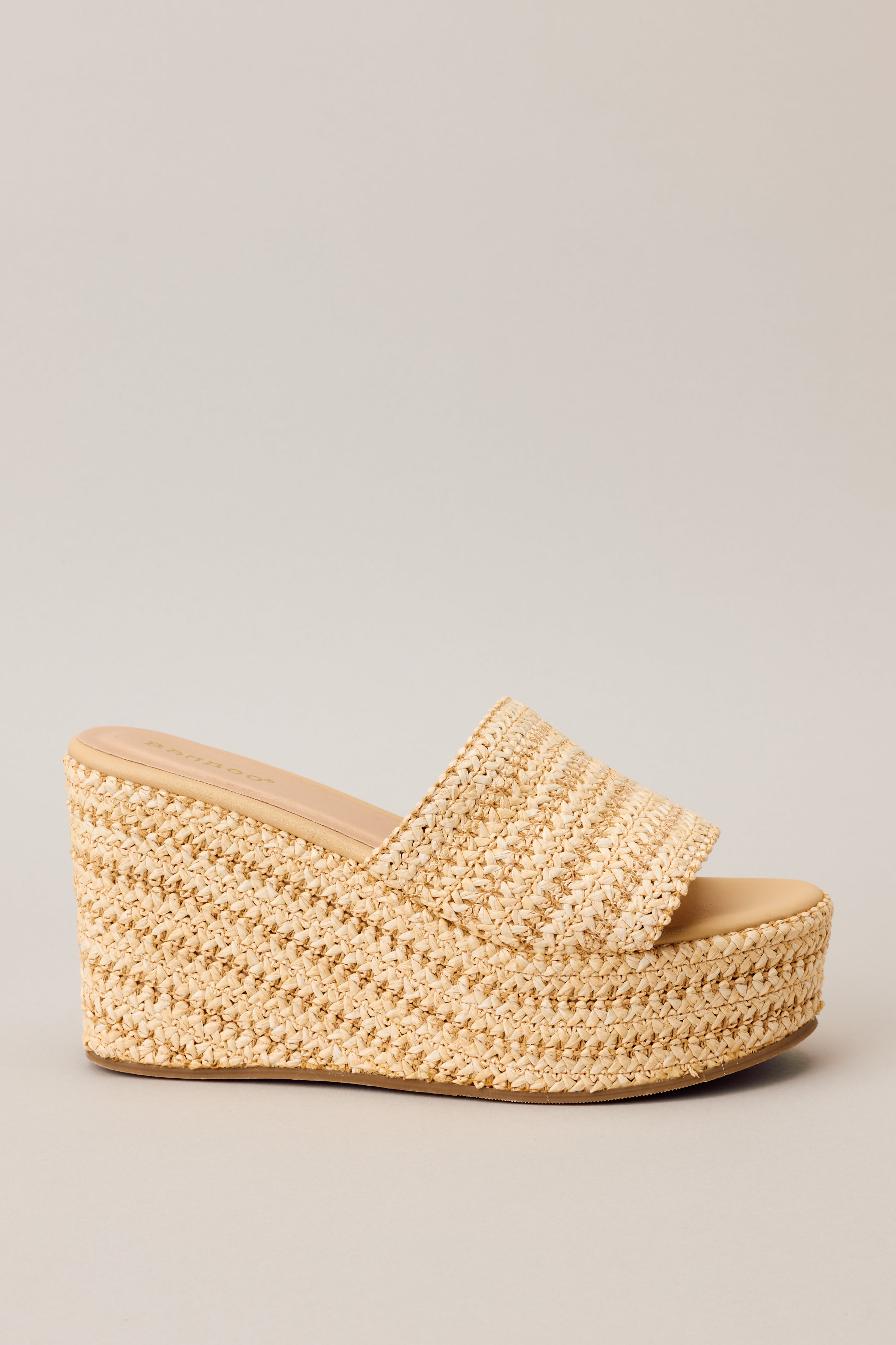 Close-up Side view of natural sandals showcasing the slide on style, raffia material, and platform design.