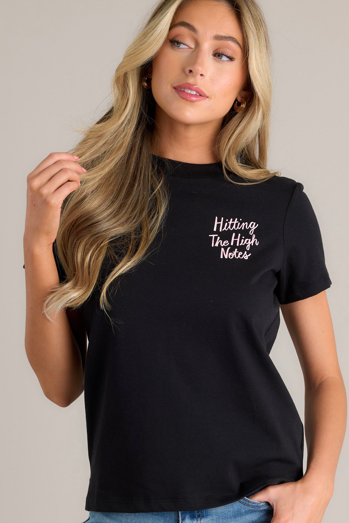 Front angled view of a black tee featuring a crew neckline, graphics on the front, short sleeves, and a relaxed fit