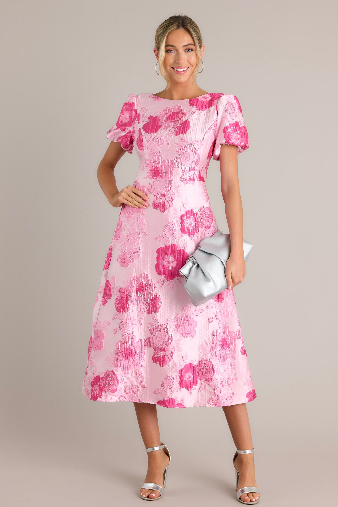 This pink dress features a boat neckline, short puff sleeves, a deep v-back with a zipper closure, and a midi length.