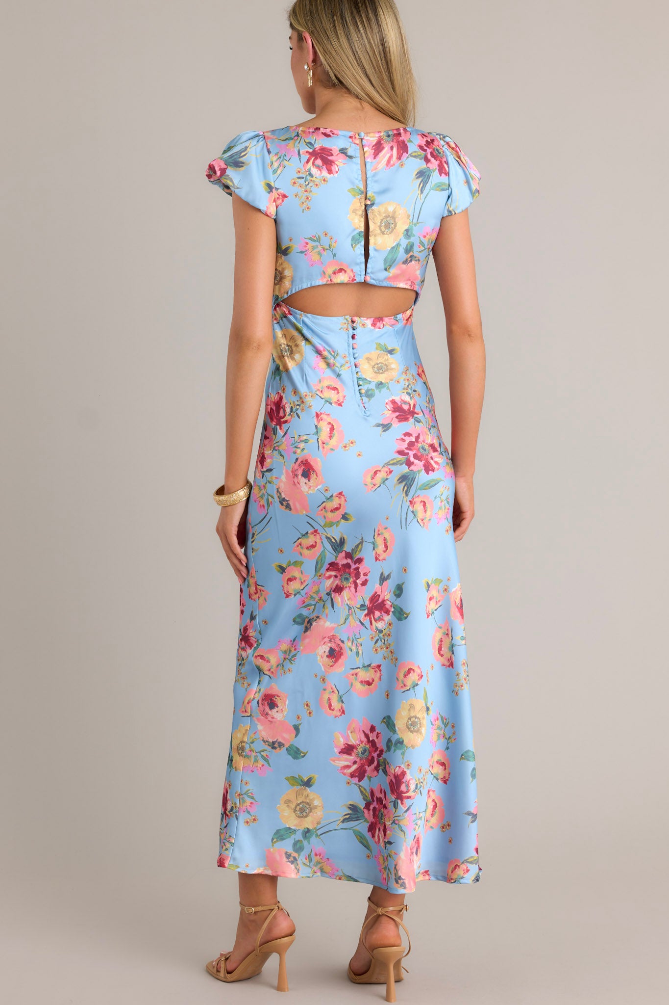 Back view of a sky blue maxi dress highlighting the functional buttons down the back and the lower back cutout.