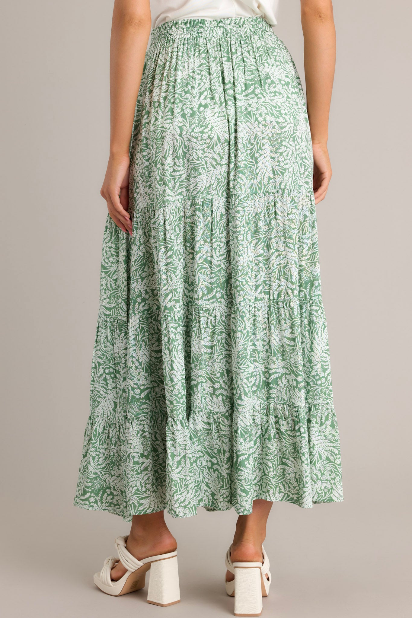 Back view of a green maxi skirt highlighting the high waisted design, elastic waistband, and overall fit.