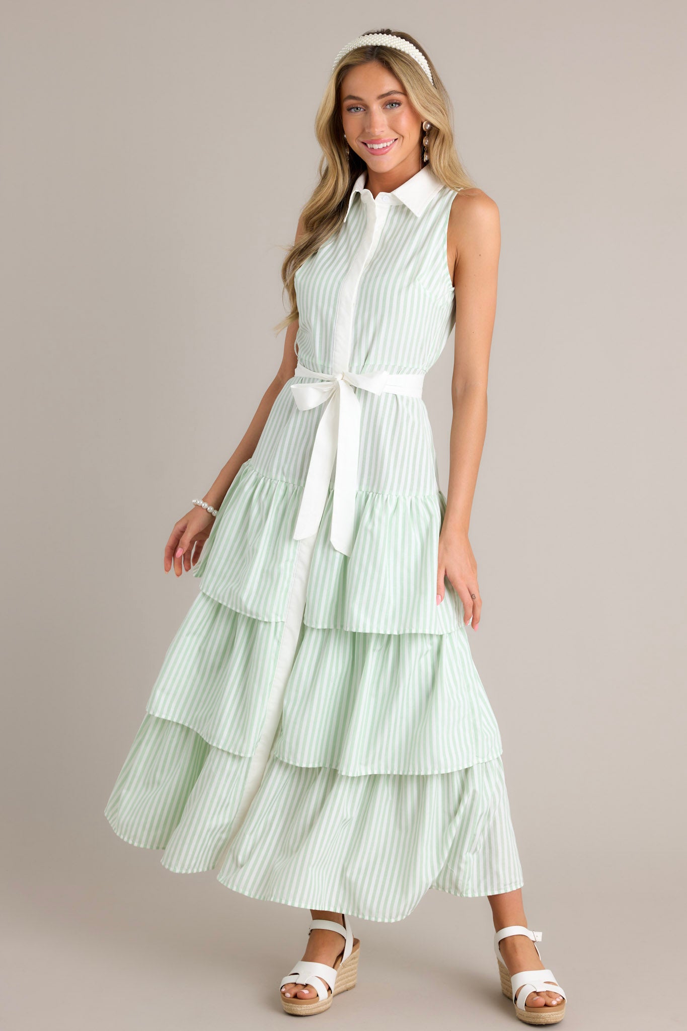 Full length view of a mint green stripe maxi dress with a collared neckline, a button front, an elastic waist insert, a self-tie waist belt, and multiple tiers