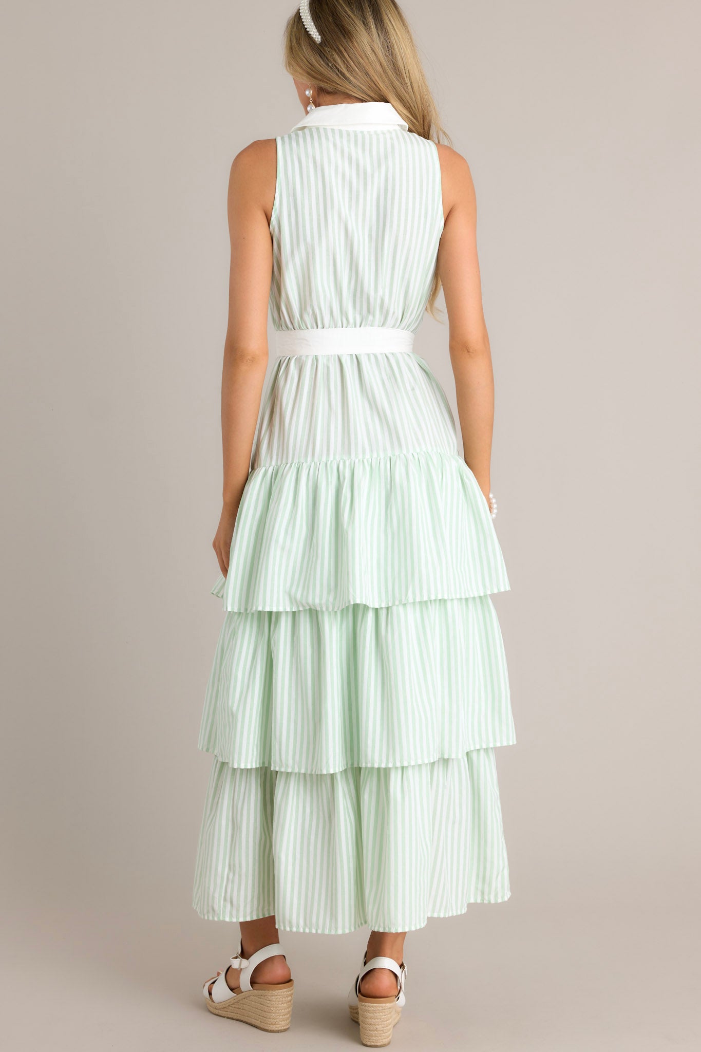 Back view of a mint green stripe maxi dress highlighting the elastic waist insert, self-tie waist belt, multiple tiers, and overall fit.