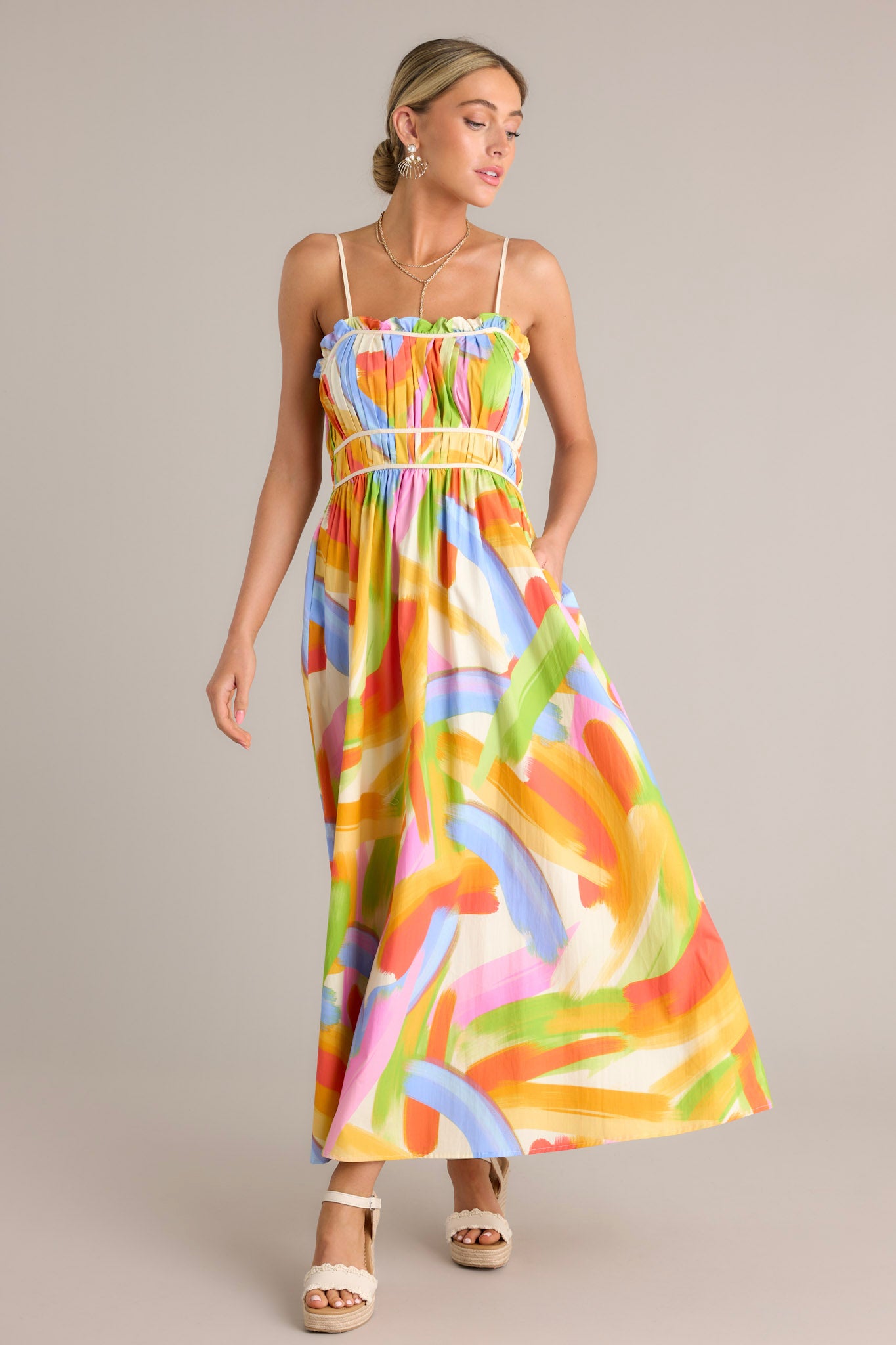 Action shot of a yellow multi maxi dress displaying the fit and movement, highlighting the square neckline, thin adjustable straps, pleated chest, elastic waist inserts, functional hip pockets, and flowing silhouette.