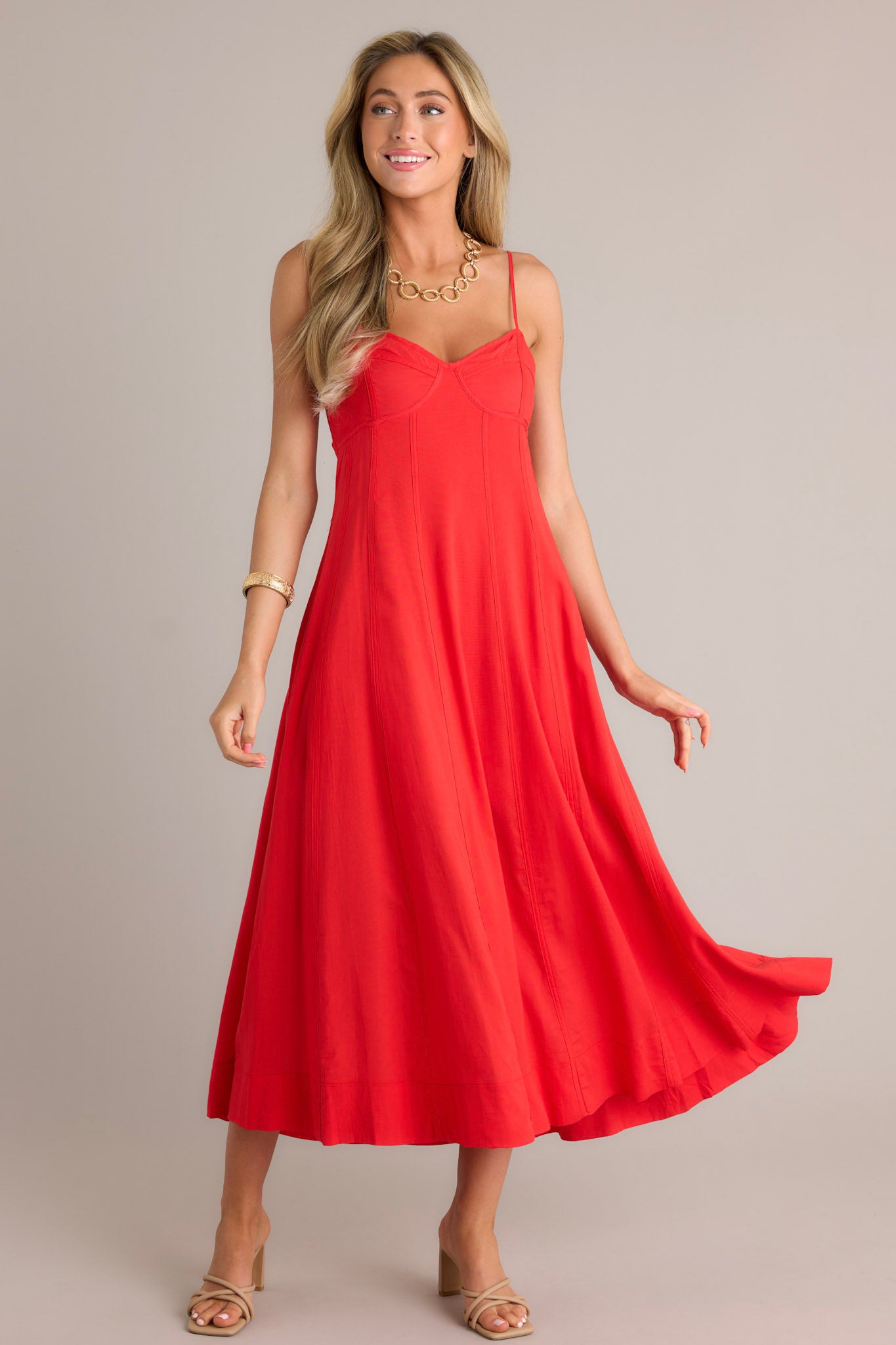 Action shot of a red maxi dress displaying the fit and movement, highlighting the sweetheart neckline, thin adjustable straps, smocked back insert, and flowing silhouette.