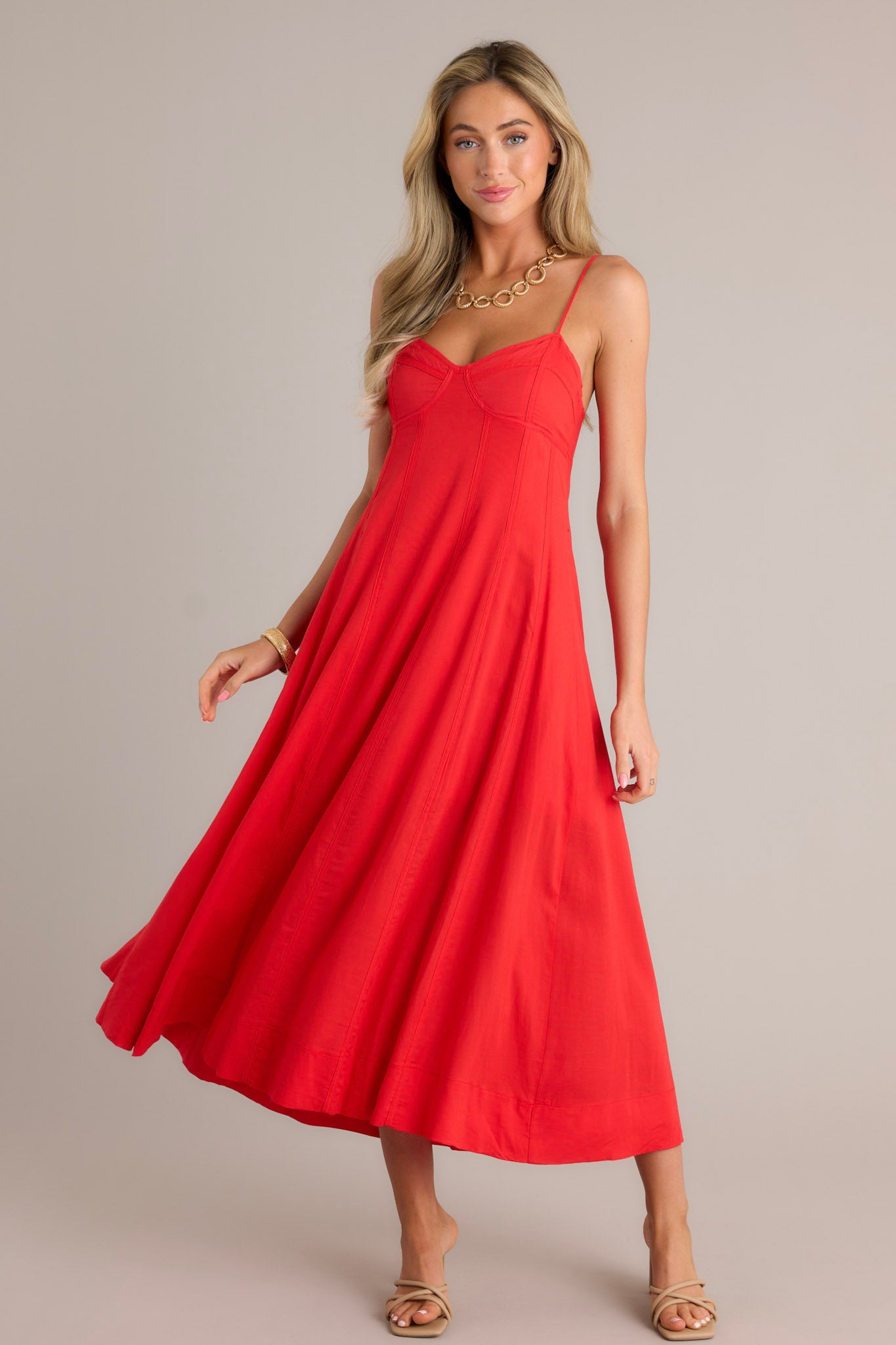 Full length view of a red maxi dress with a sweetheart neckline, thin adjustable straps, no boning in the bodice for a bustier look, a smocked back insert, a discrete zipper, and a flowing silhouette