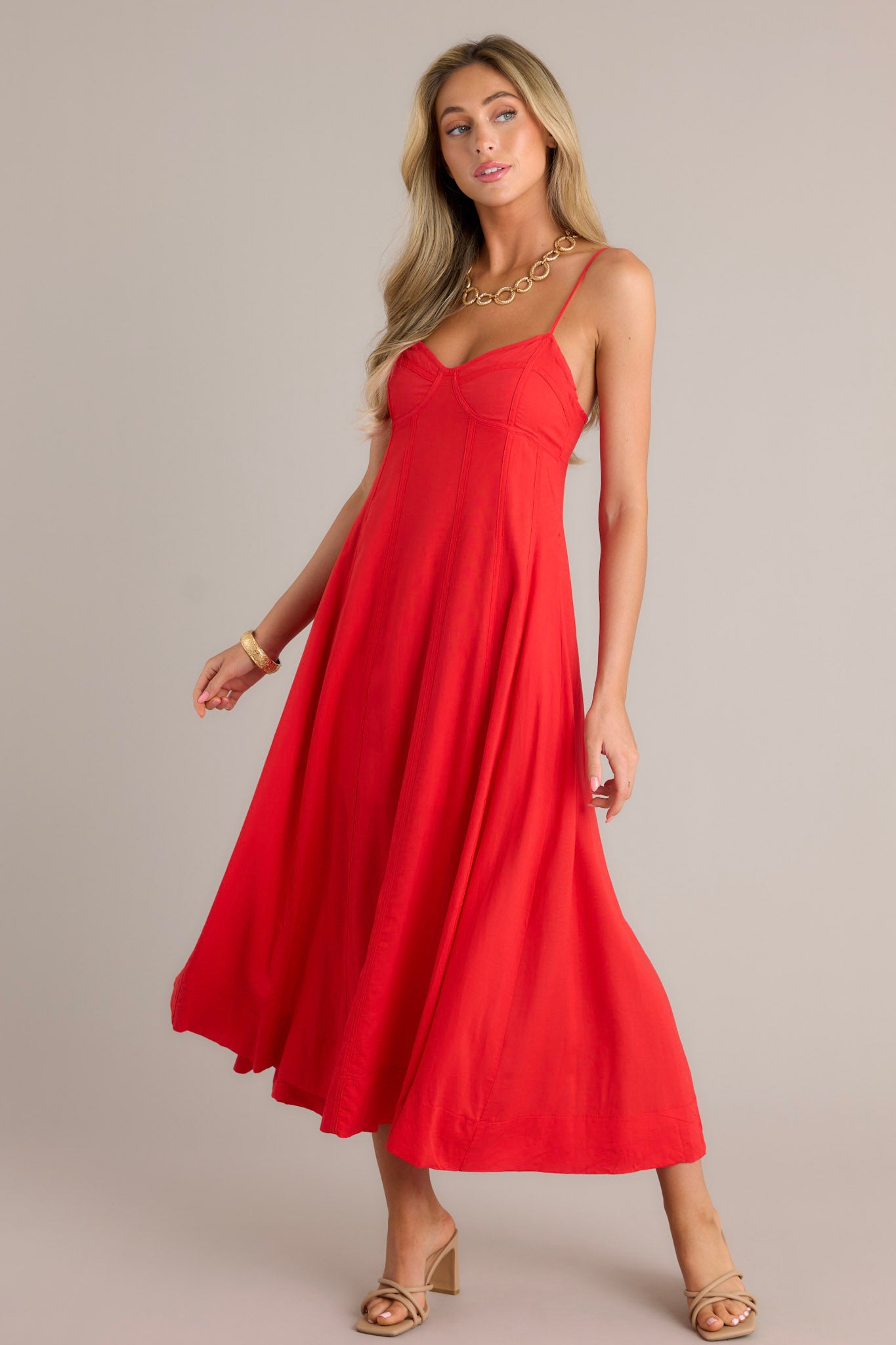 Side view of a red maxi dress showcasing the sweetheart neckline, thin adjustable straps, smocked back insert, discrete zipper, and flowing silhouette.