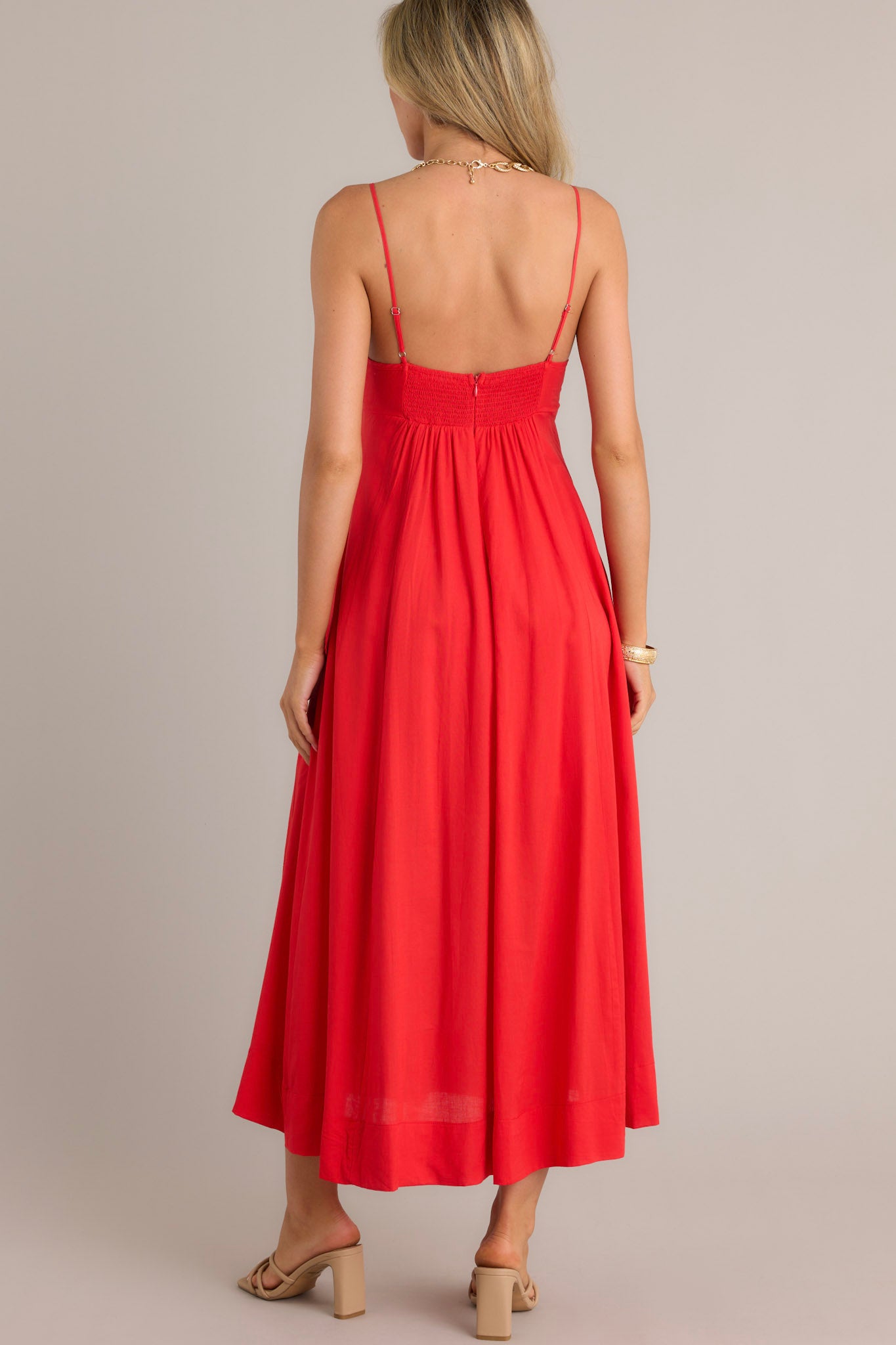 Back view of a red maxi dress highlighting the smocked back insert, thin adjustable straps, and overall fit.