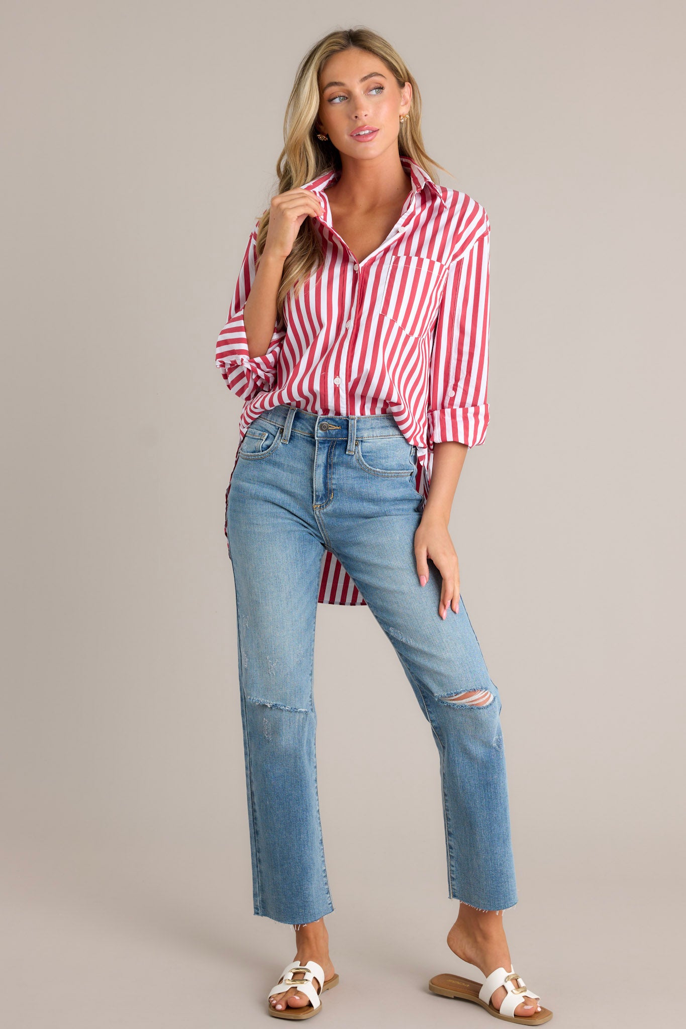 Full length view of a red stripe top with a collared neckline, a functional button front, a breast pocket, rollable button cuffed sleeves, and a split high-low hemline