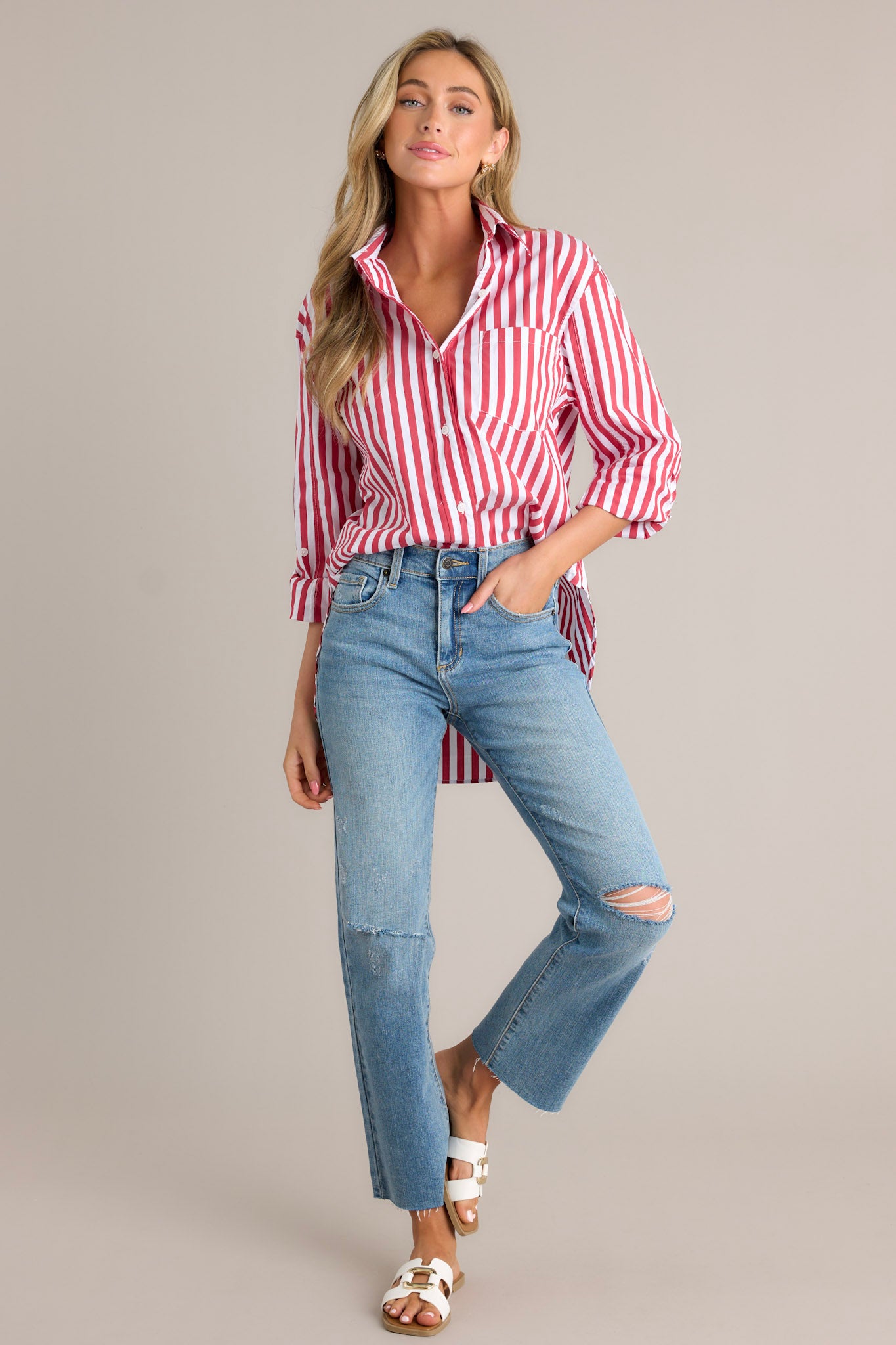 Action shot of a red stripe top displaying the fit and movement, highlighting the collared neckline, functional button front, breast pocket, rollable button cuffed sleeves, and split high-low hemline.