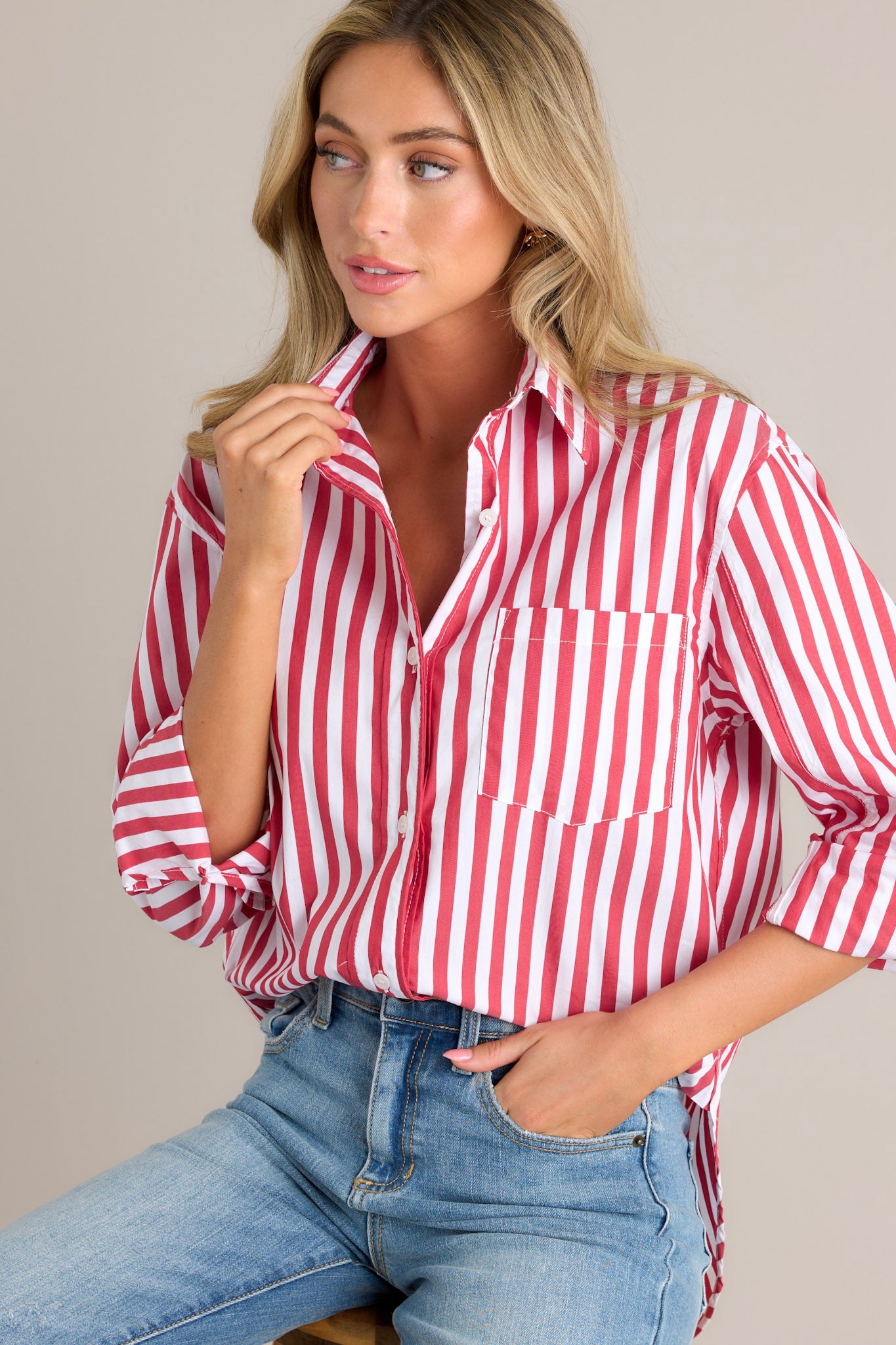 This red stripe top featured a collared neckline, a functional button front, a breast pocket, rollable button cuffed sleeves, and a split high-low hemline.