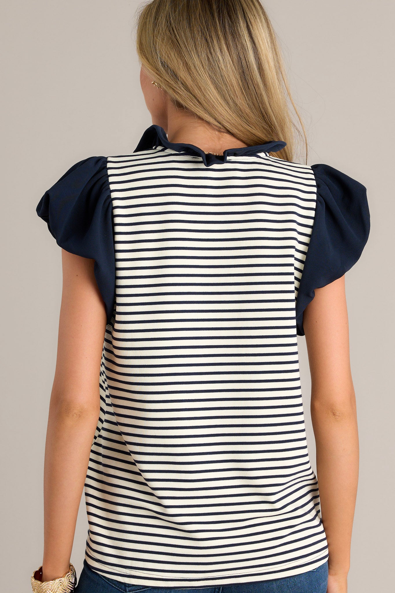 Back view of a beige stripe blouse highlighting the overall fit, navy and beige horizontal stripes, and slightly cuffed short sleeves.