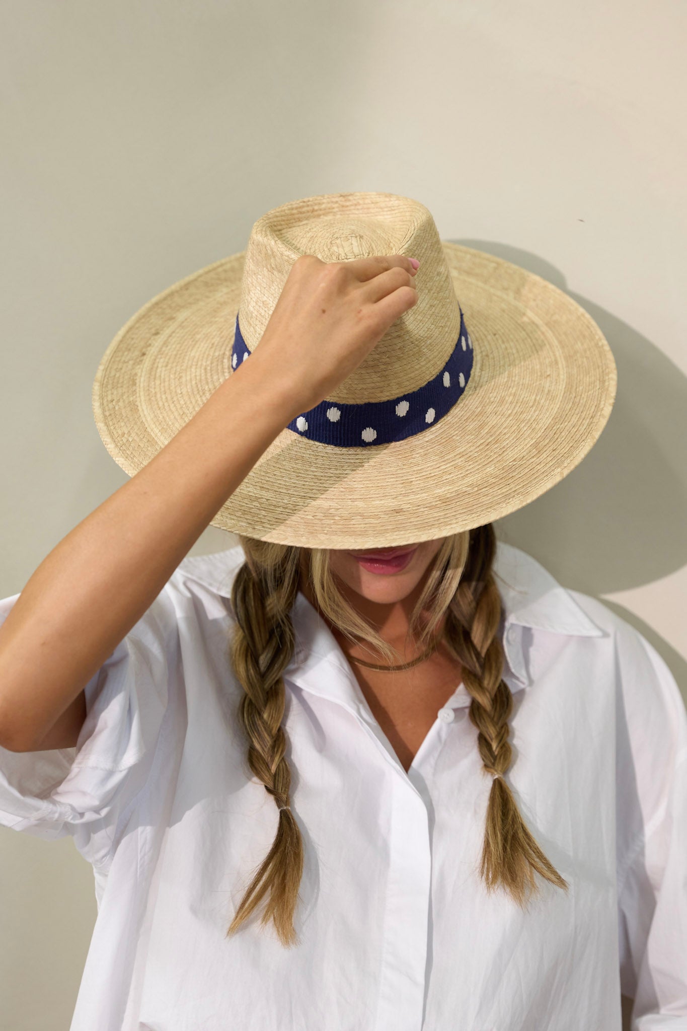 Tilted view of this Wendy hat features a navy, cotton woven band with white polka dots.