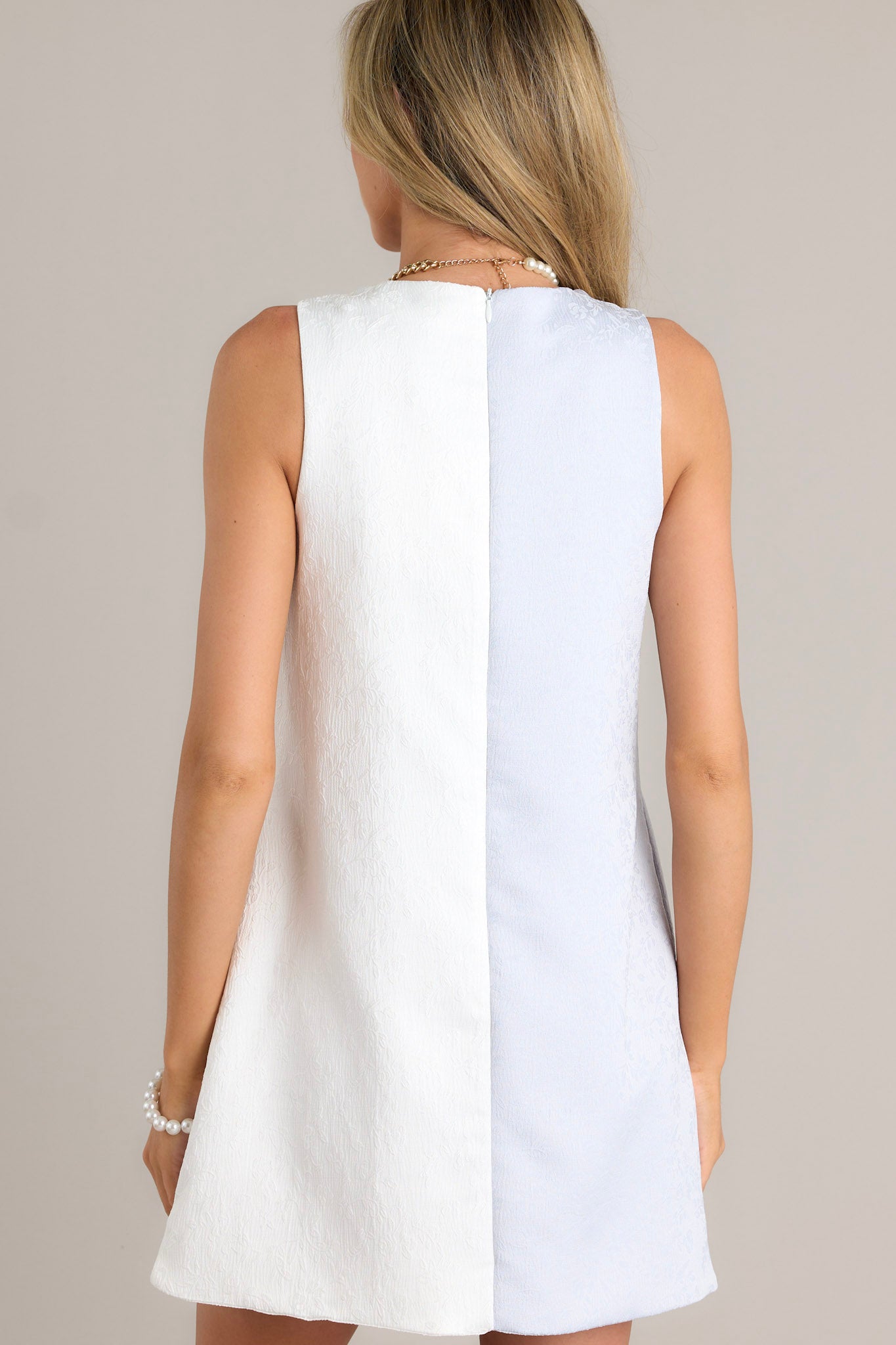 Back view of a light blue mini dress highlighting the overall fit, color block design, and sleeveless design.