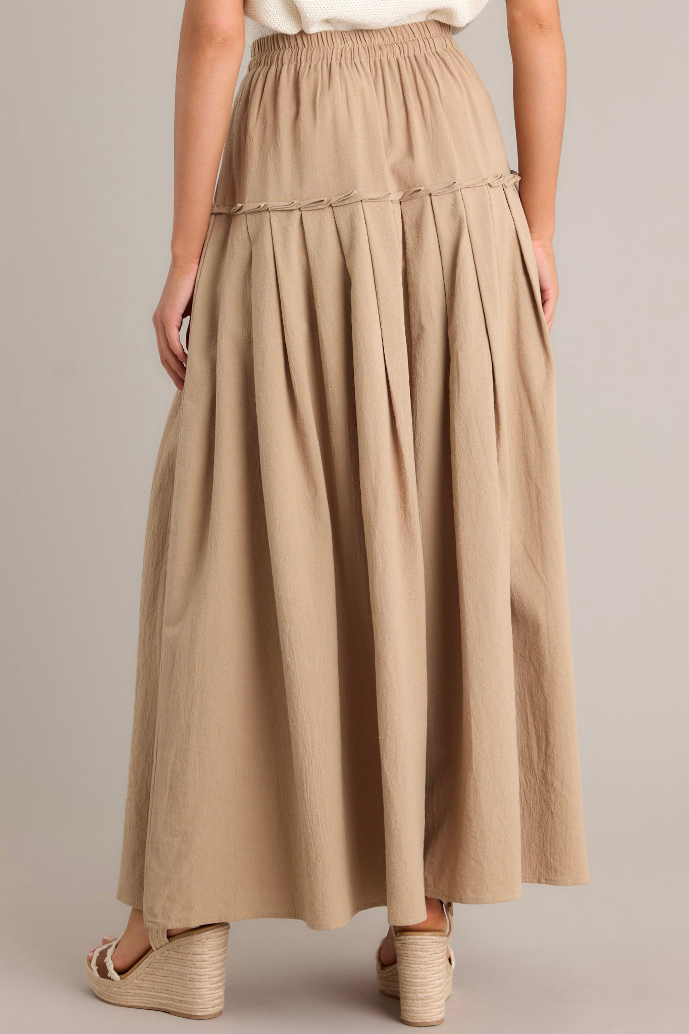 Back view of a beige maxi skirt highlighting the single tier, subtle pleats, and overall fit.