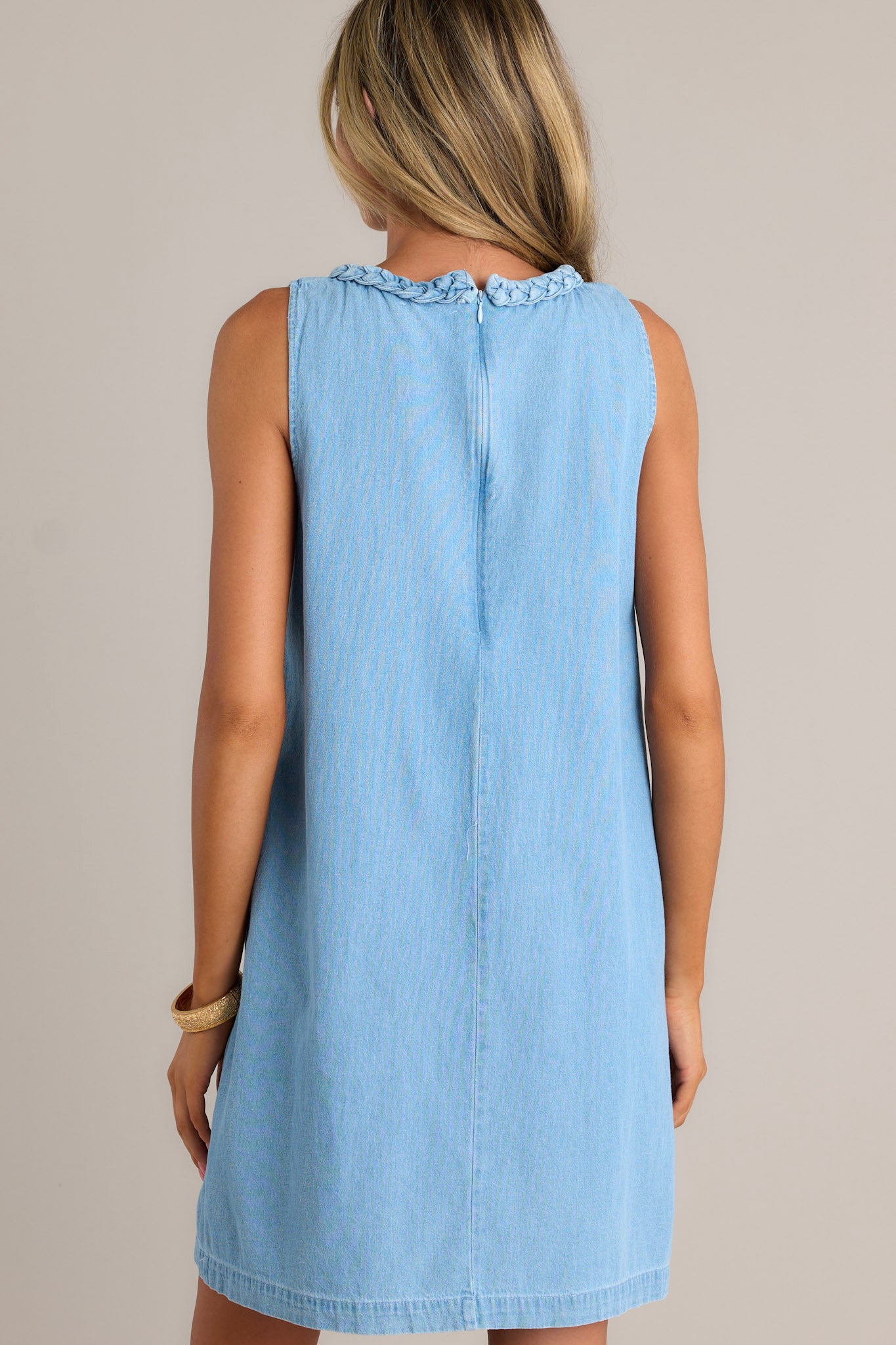 Back view of a light blue dress highlighting the discrete zipper, braided detailing, and overall fit.