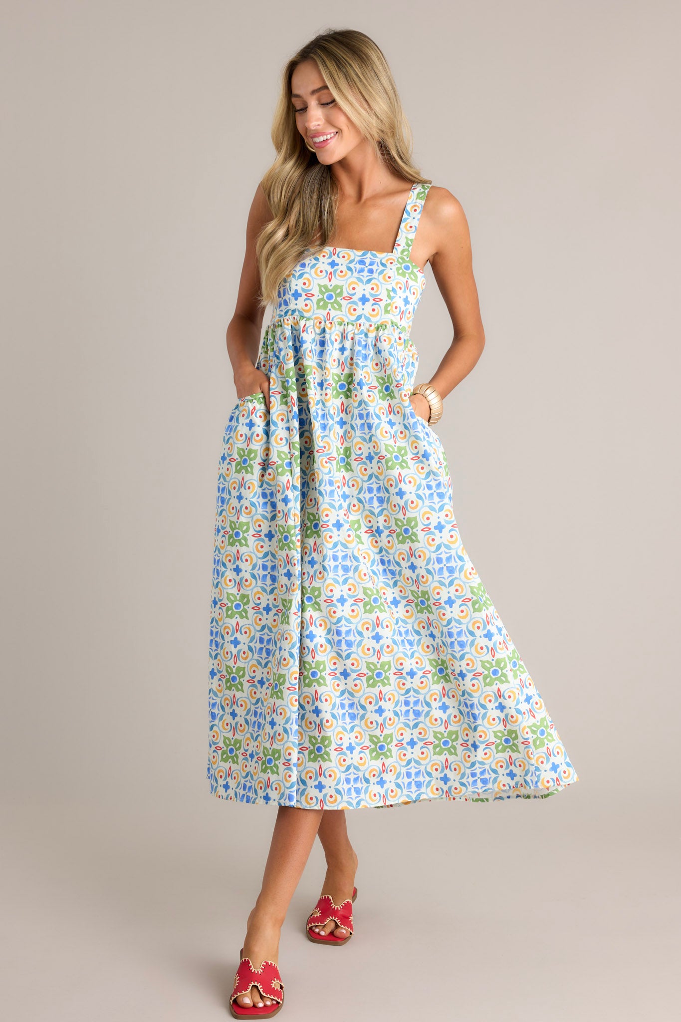 Action shot of a white midi dress displaying the fit and movement, highlighting the square neckline, self-tie adjustable straps, colorful pattern, functional hip pockets, and flowing silhouette.