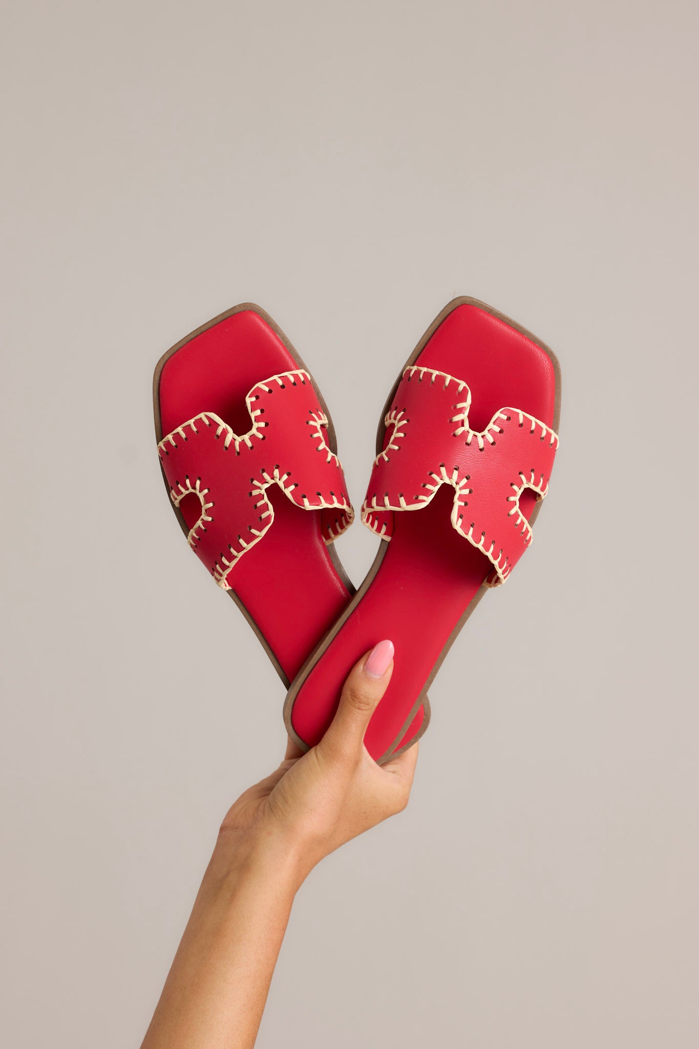 Top view of these red sandals that feature a square toe, a slip on design, a strap with cutouts over the top of the foot beige stitch detailing, and a high contrasting sole.