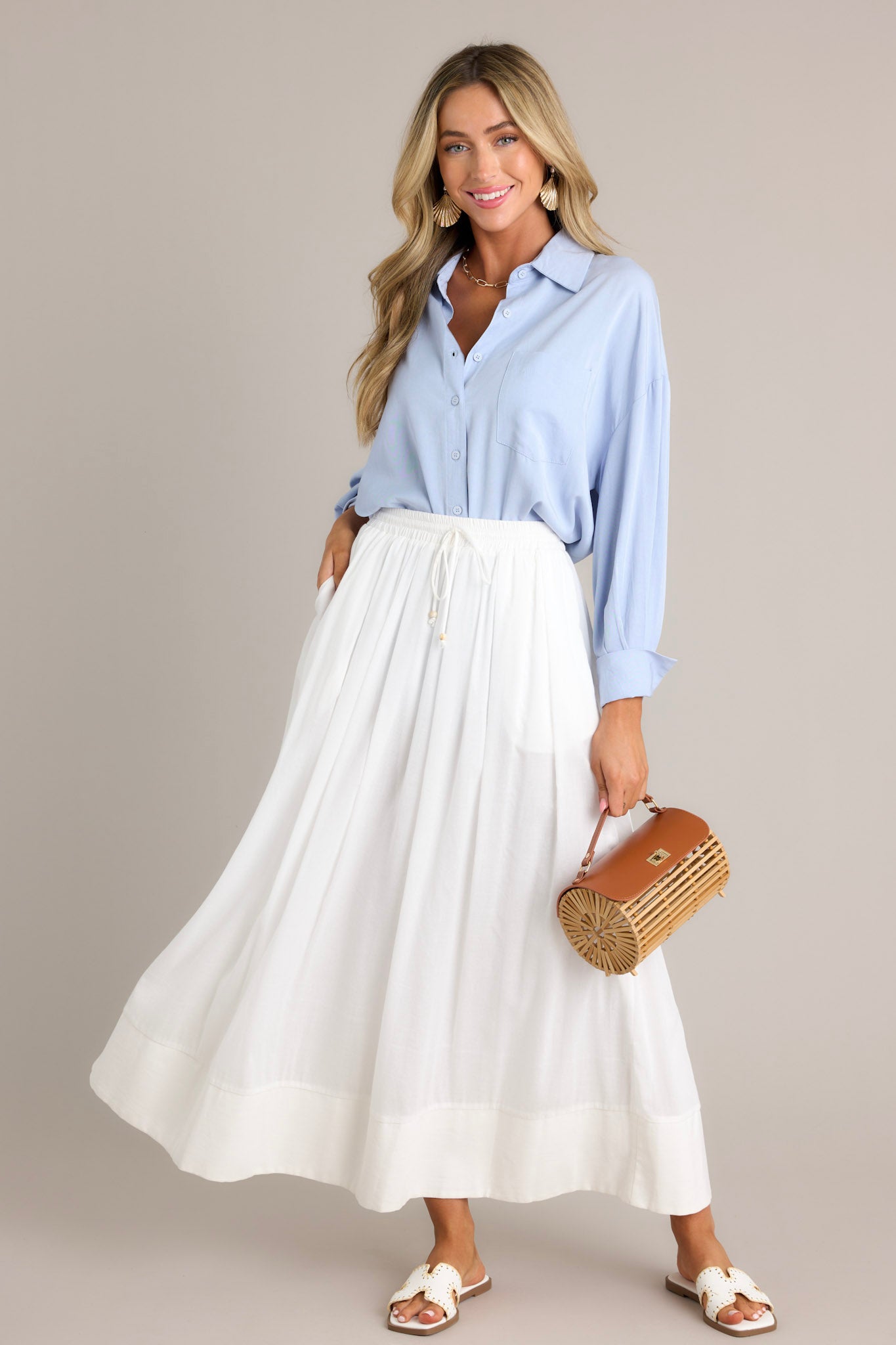 Full length view of a light blue top featuring a collared neckline, functional buttons down the front, a chest pocket, a dropped shoulder, and button cuffed long sleeves