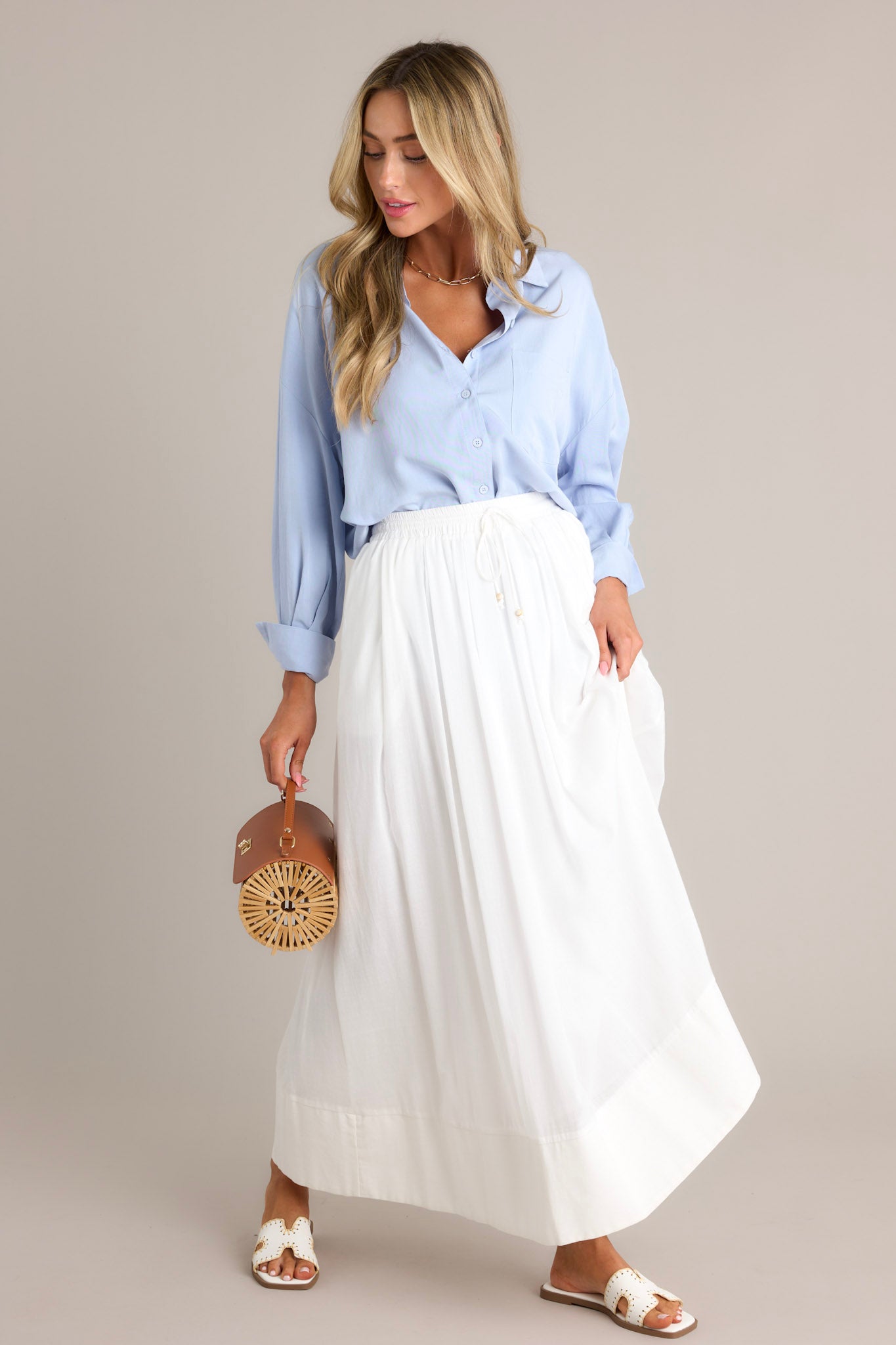 Front view of a light blue top featuring a collared neckline, functional buttons down the front, a chest pocket, a dropped shoulder, and button cuffed long sleeves.